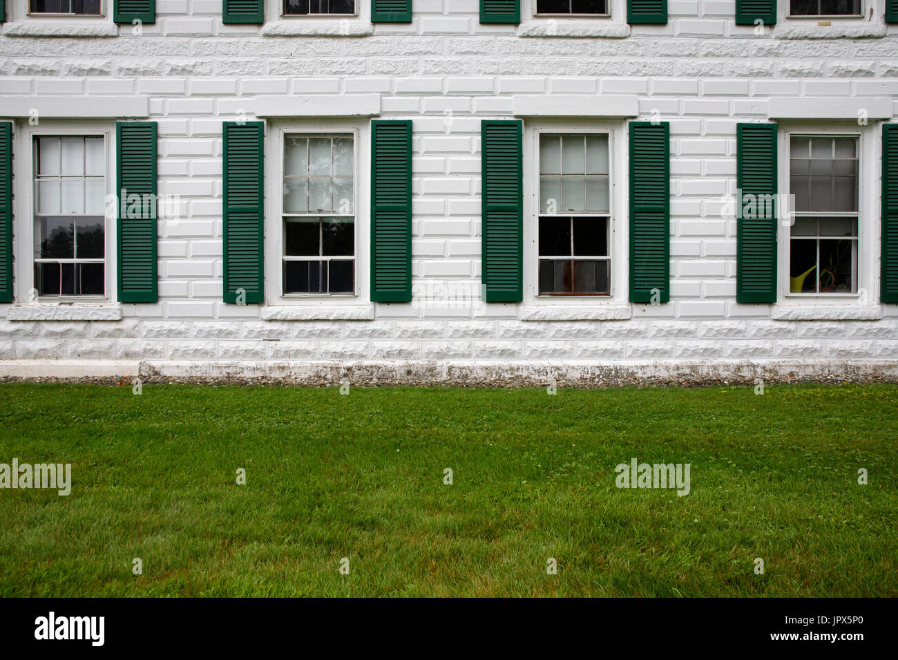 Bianco pietra mattoni facciata di edificio file di windows persiane verdi Foto Stock