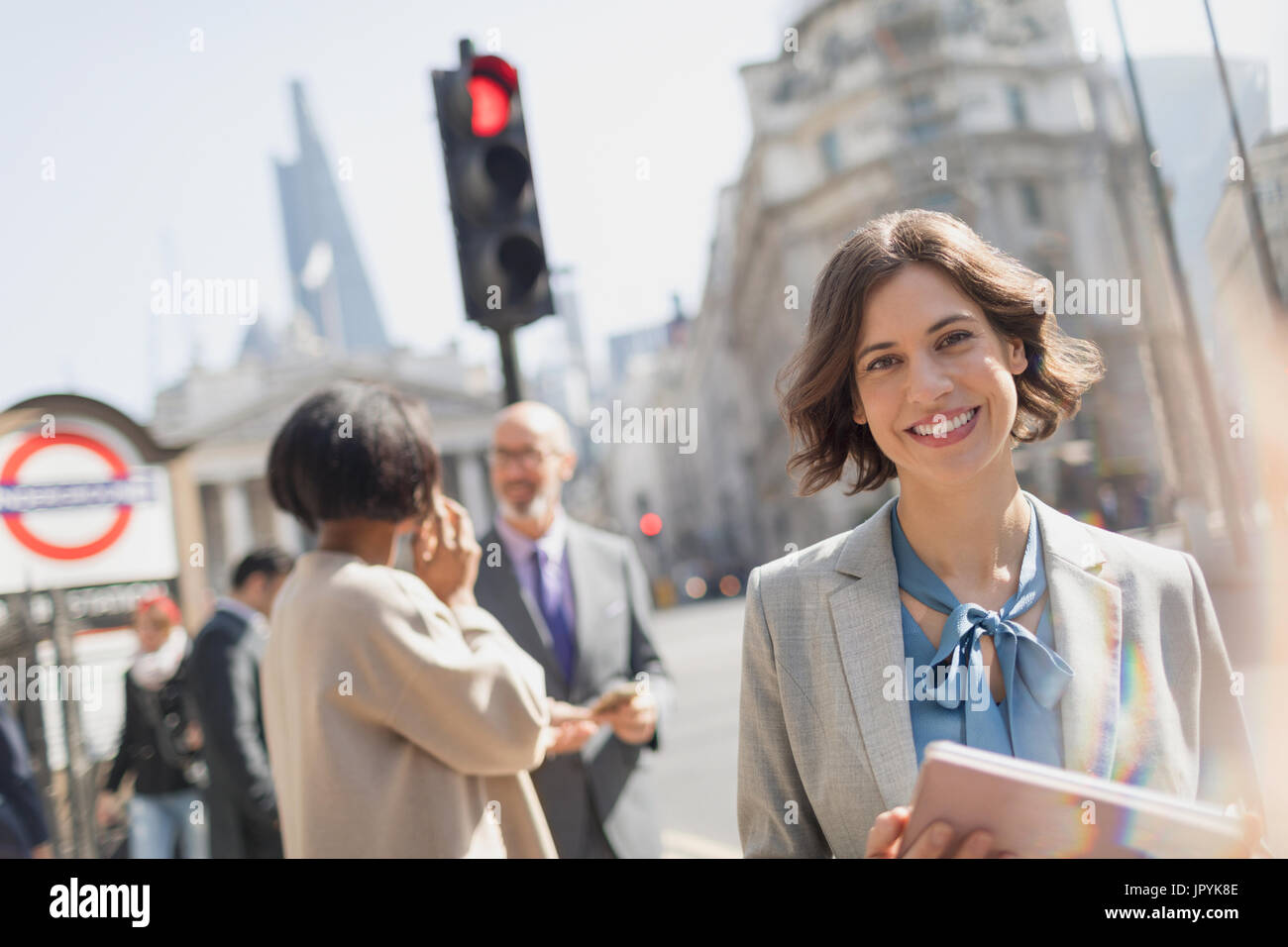 Ritratto sorridente, fiduciosi imprenditrice sulla soleggiata città urban street Foto Stock