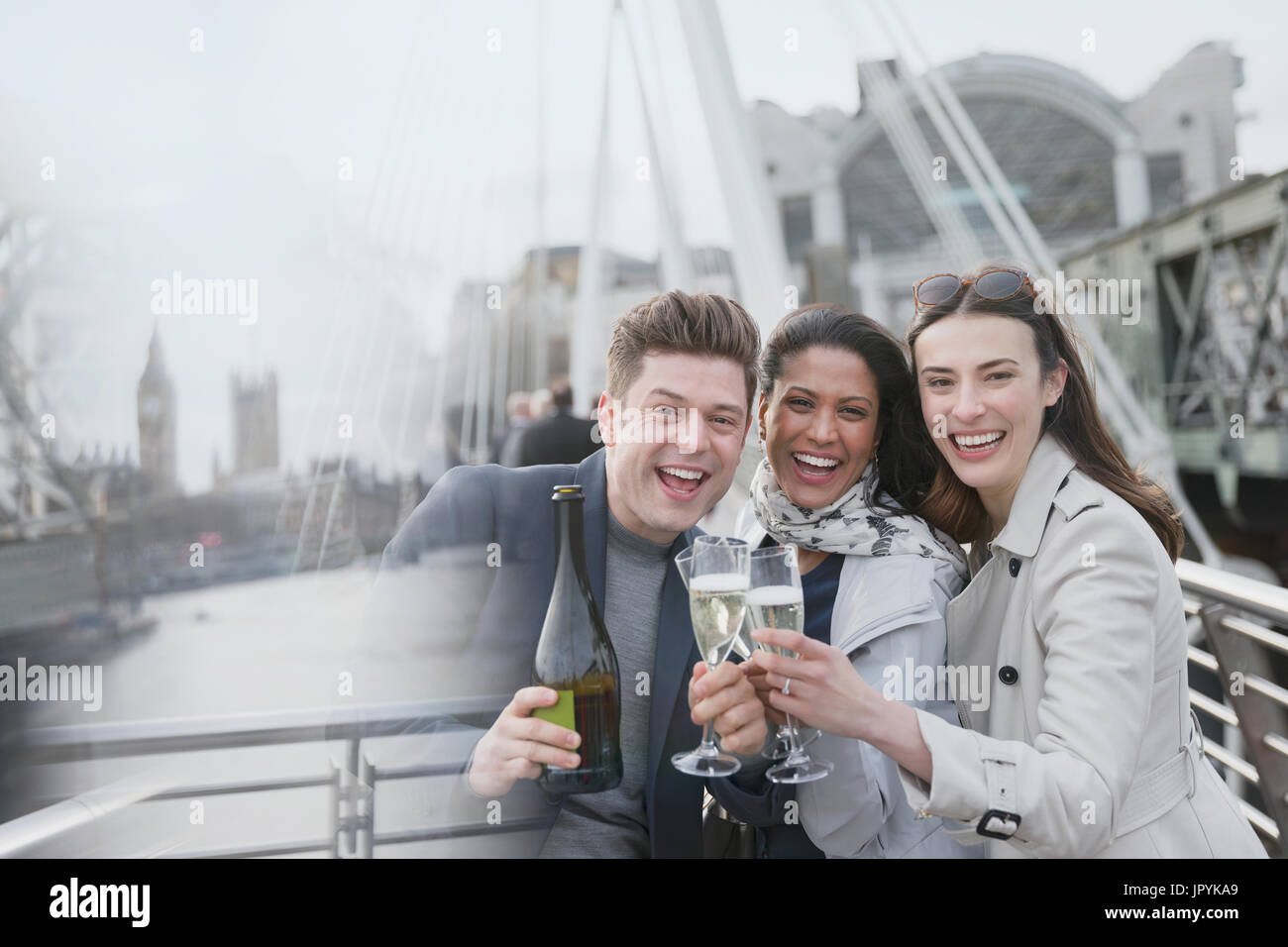 Ritratto aziendale entusiasta persone celebrando, tostatura champagne sul ponte urbano, London, Regno Unito Foto Stock