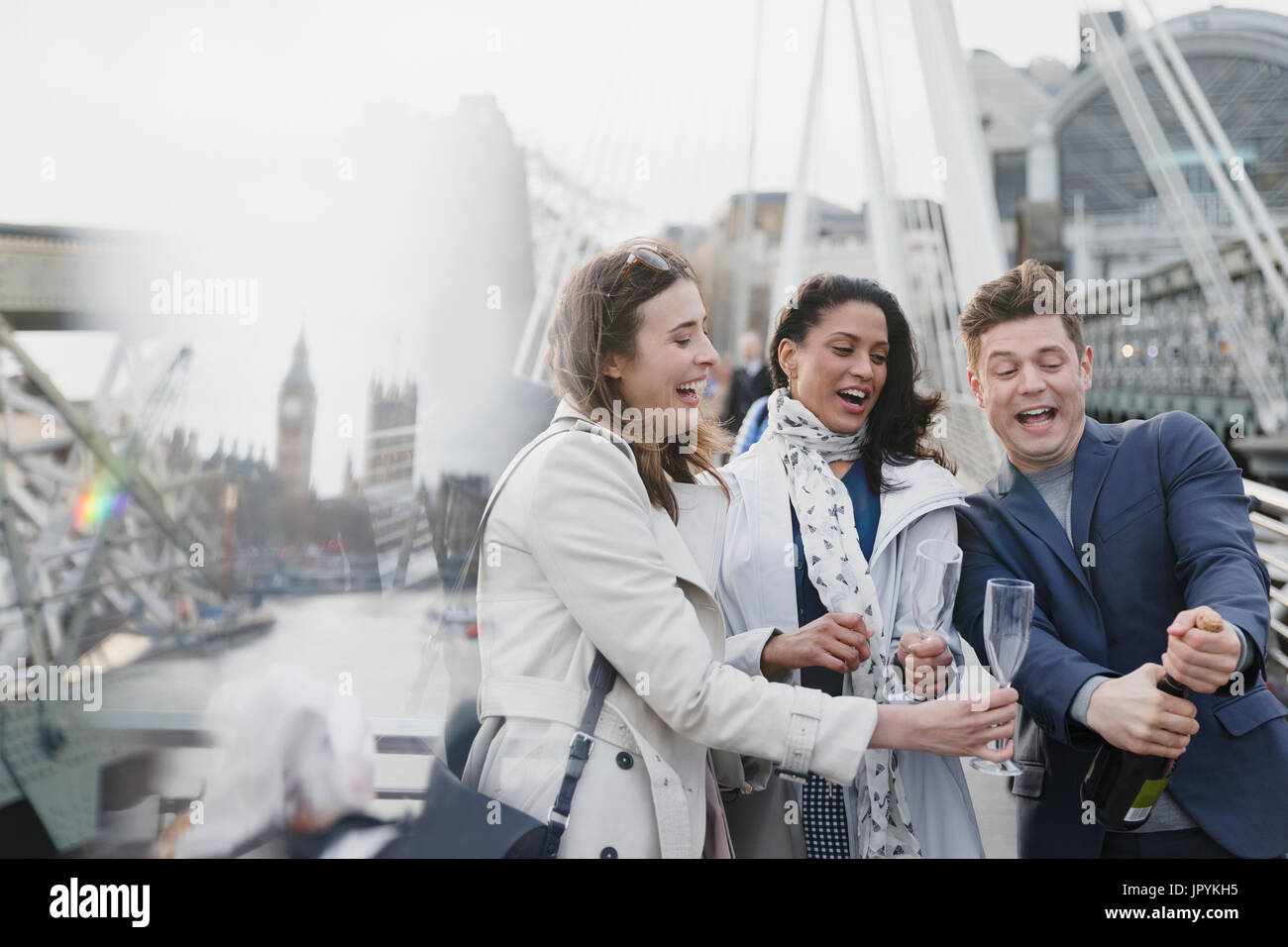Gli amici di popping champagne, celebrando sul ponte urbano, London, Regno Unito Foto Stock