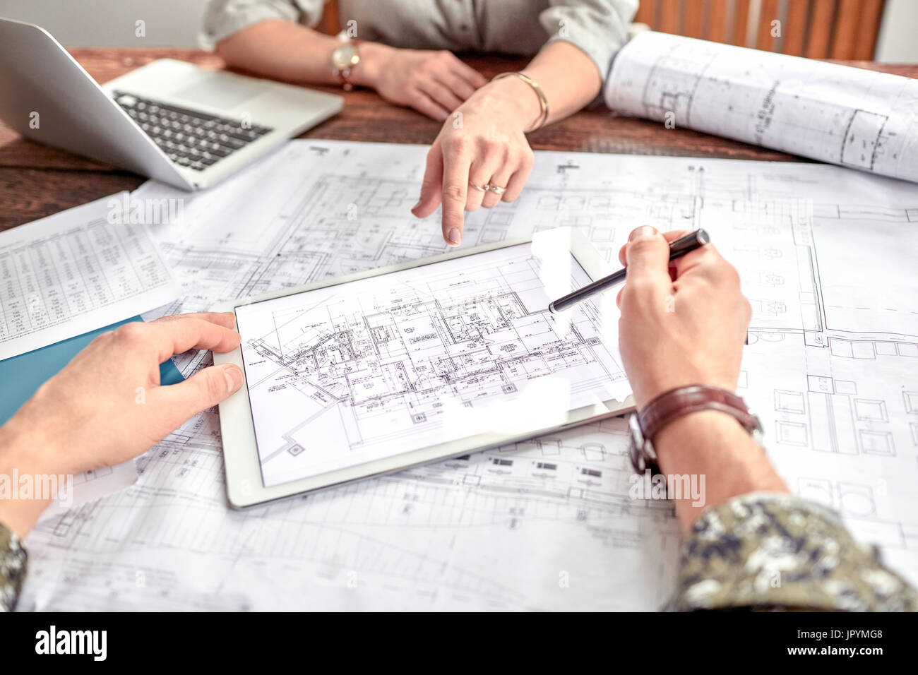 Architetti esaminando e discutendo complesso blueprint digitale in riunione Foto Stock