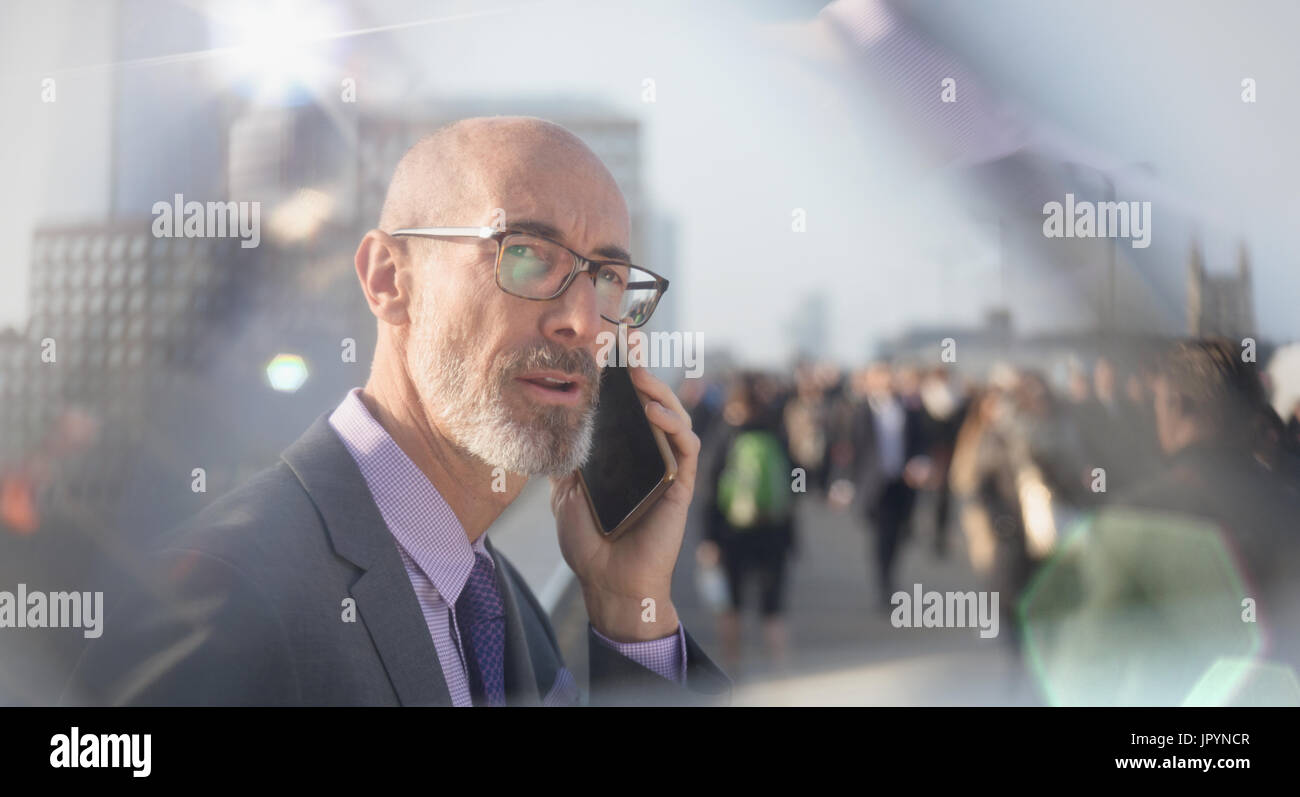 Imprenditore serio parlando al cellulare su strada urbana Foto Stock