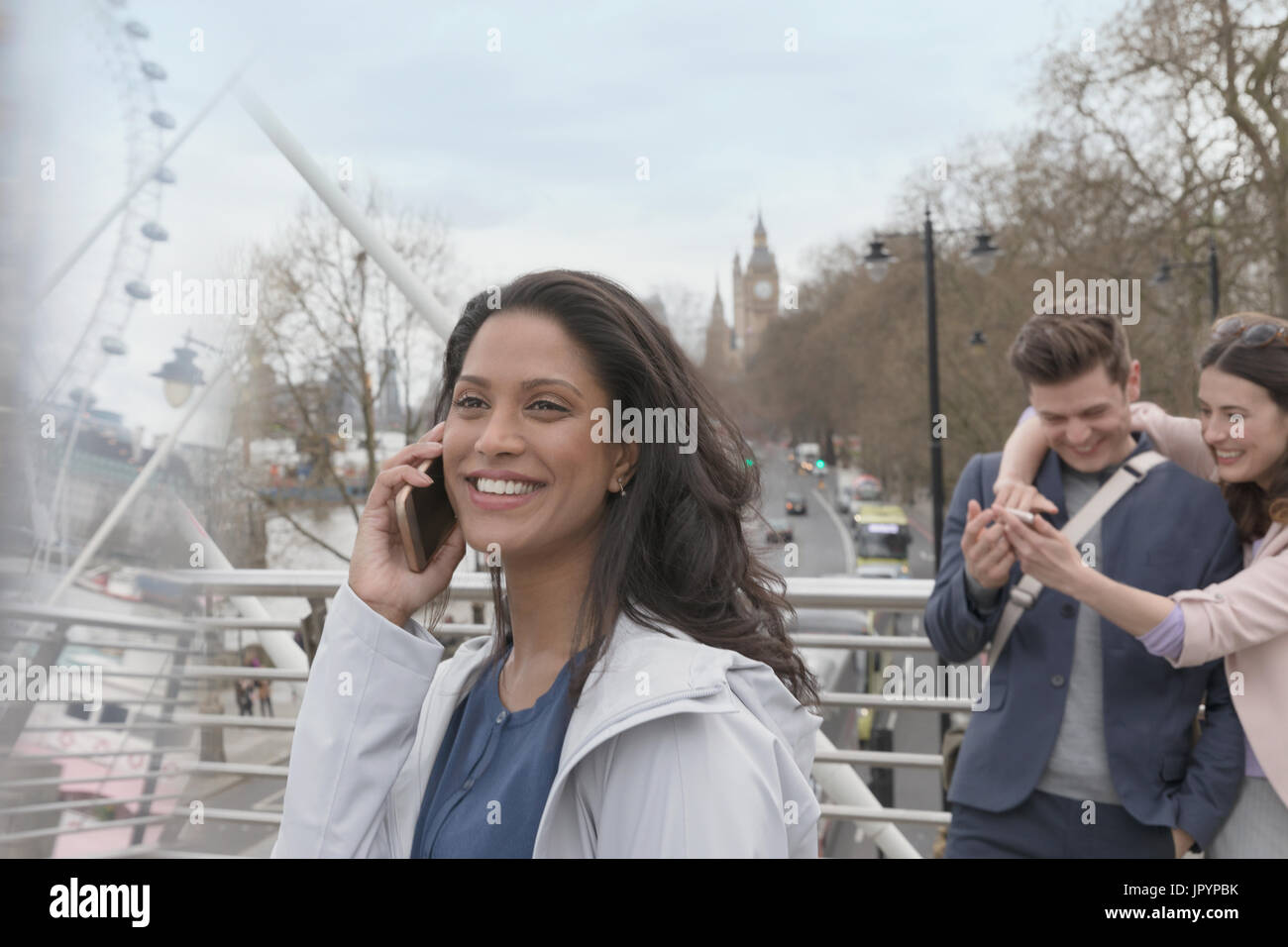 Donna sorridente parlando al cellulare sul ponte urbano, London, Regno Unito Foto Stock