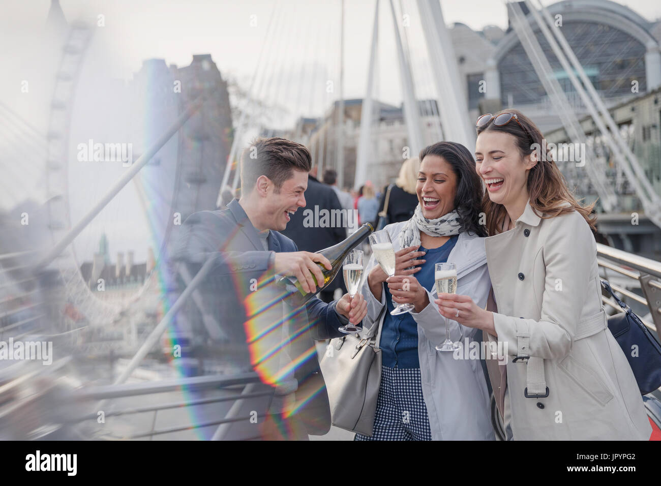 Sorridono felici amici celebrando, versando champagne nella city di Londra, Regno Unito Foto Stock