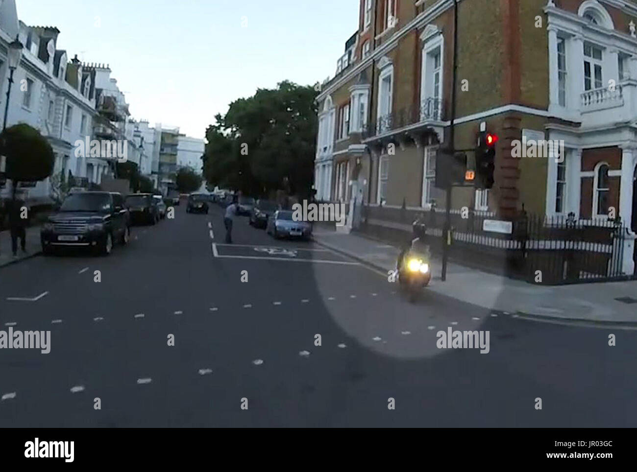 Immagine catturata dallo schermo ripresa dai filmati emessi dalla polizia metropolitana di ladri che cavalcano in fuga dopo aver adoiato un uomo (centro, sfondo) con liquidi vicino al grande magazzino Harrods di Londra. Foto Stock