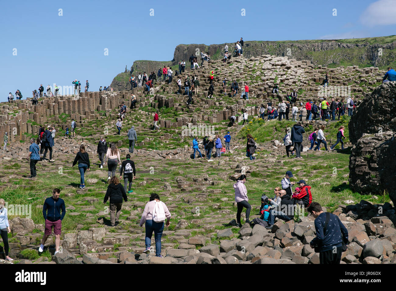 I turisti di arrampicata di colonne di basalto a Selciato del gigante con porta Reostan viewpoint in background Antrim Irlanda del Nord Foto Stock