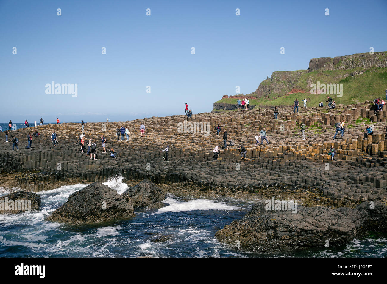 I turisti di arrampicata di colonne di basalto a Selciato del gigante con porta Reostan viewpoint in background Antrim Irlanda del Nord Foto Stock