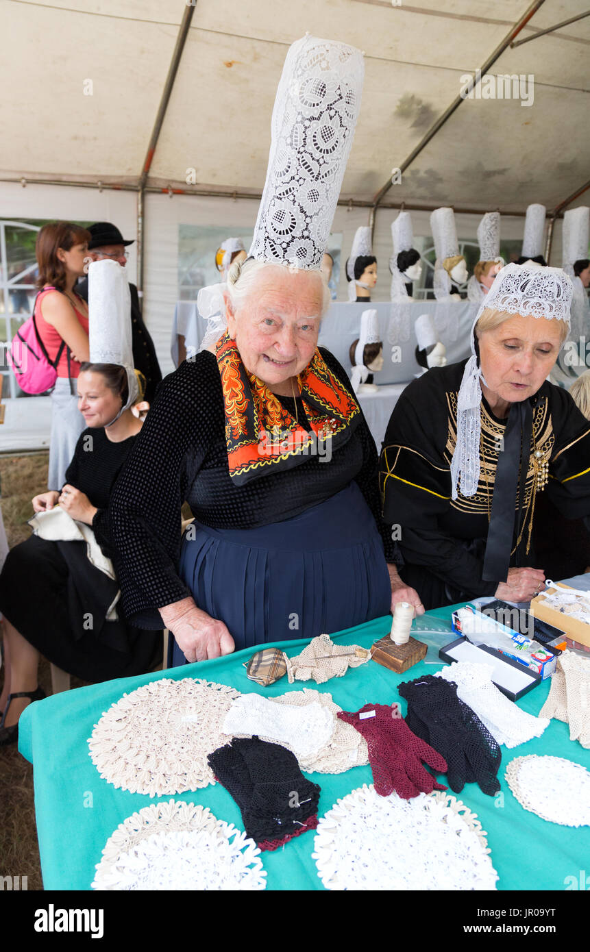 Un senior donna in costume tradizionale merletto di vendita in un mercato in stallo, Pont L'Abbe, Bretagna Francia Europa Foto Stock