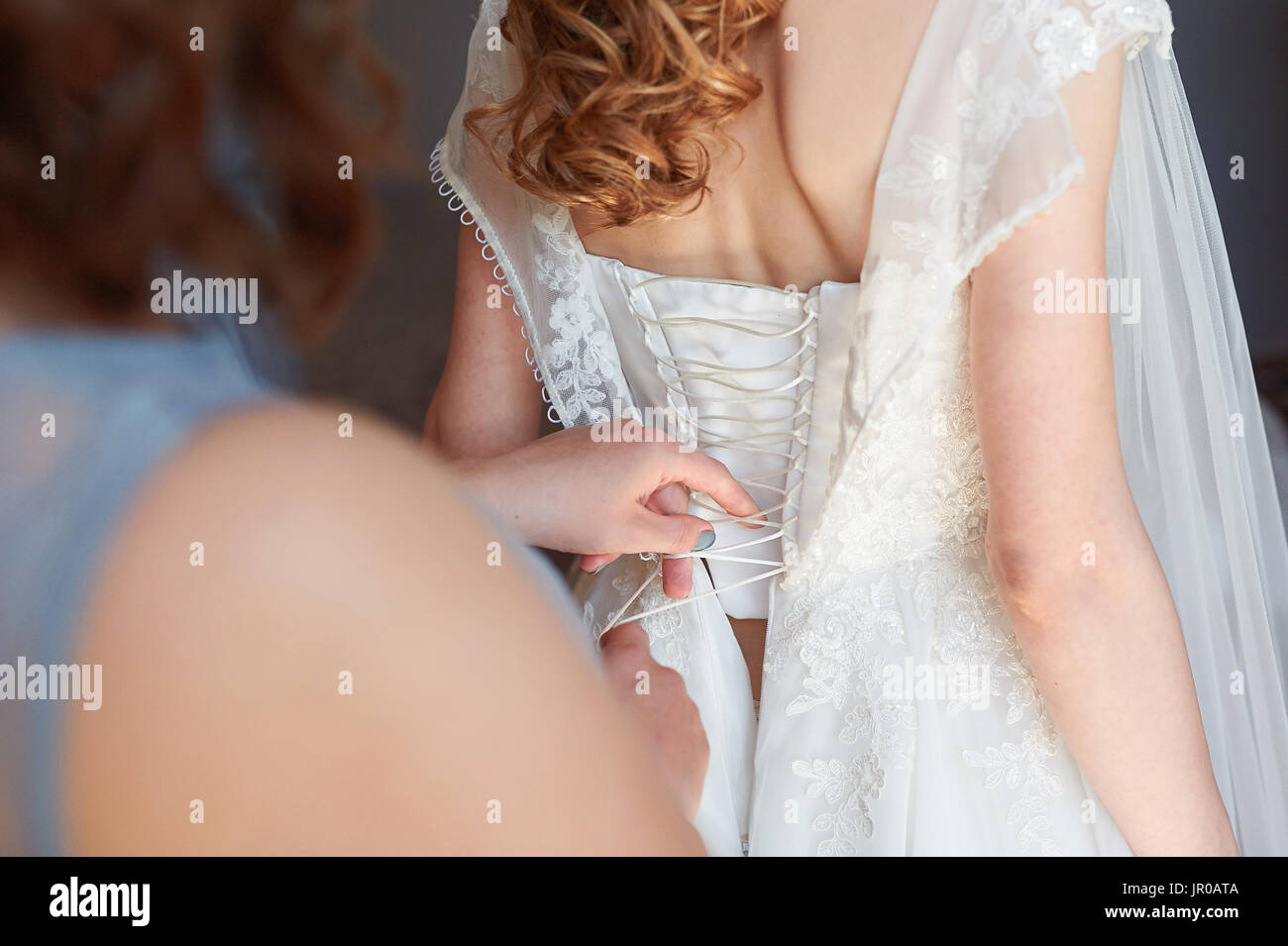 Damigella aiuta a abito da sposa nel giorno del matrimonio Foto Stock