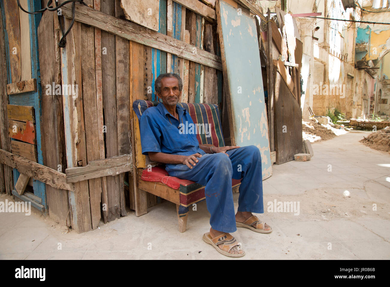 Un cubano di uomo si siede di fronte al suo improvvisati capanna in legno casa costruita all'interno di uno sbriciolamento coloniale in Havana Cuba Foto Stock