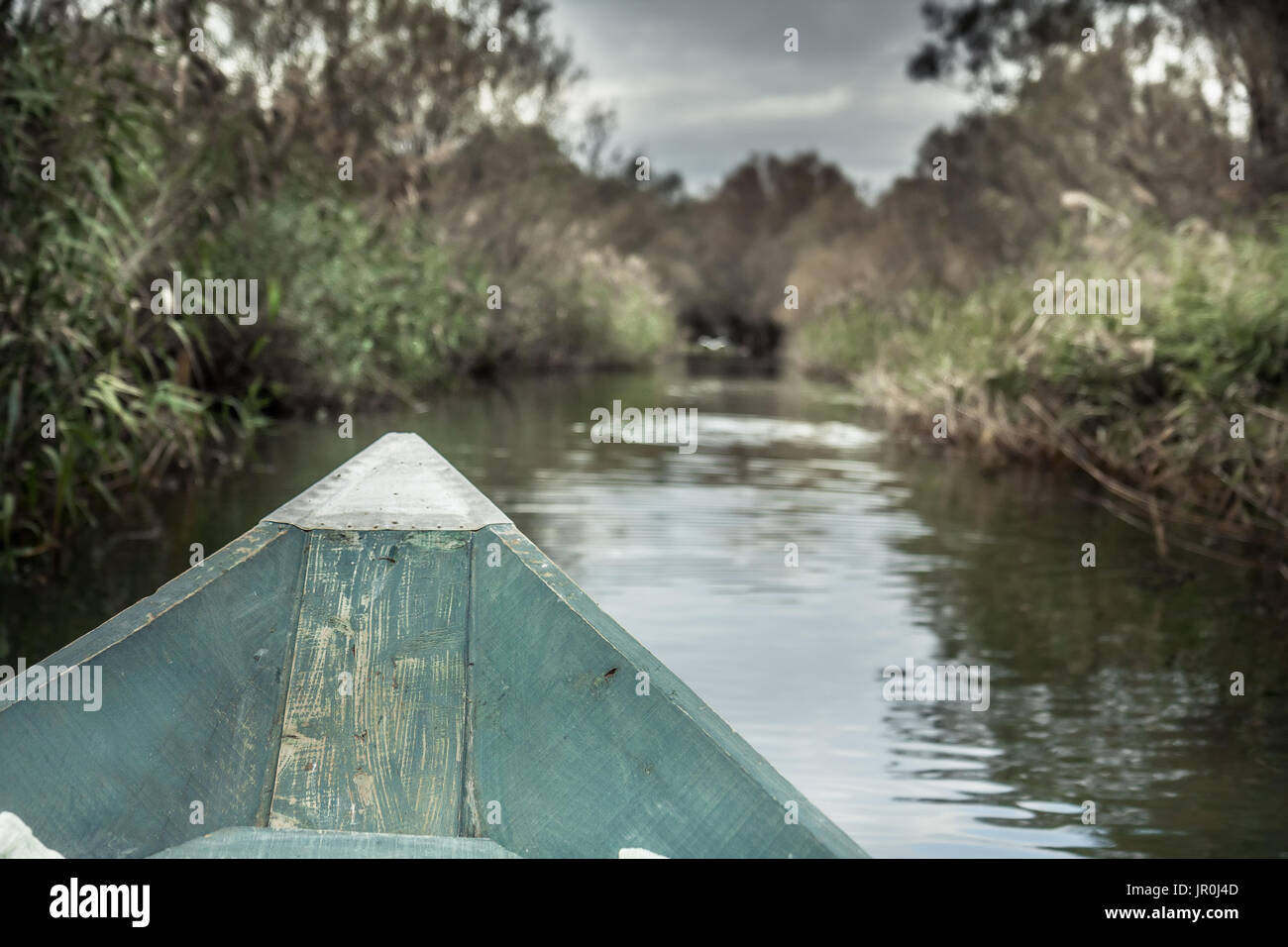 Prua della barca con direzione di avanzamento verso la banca sul fiume nel giorno nuvoloso con drammatica sky Foto Stock