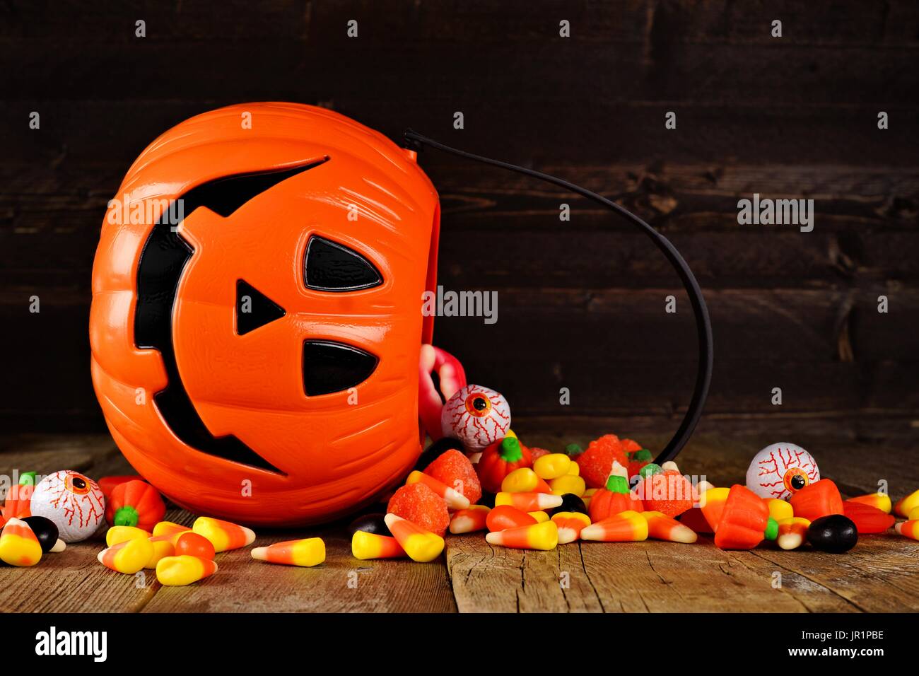 Halloween Jack o Lantern candy titolare con fuoriuscita di caramella sul legno rustico sfondo Foto Stock