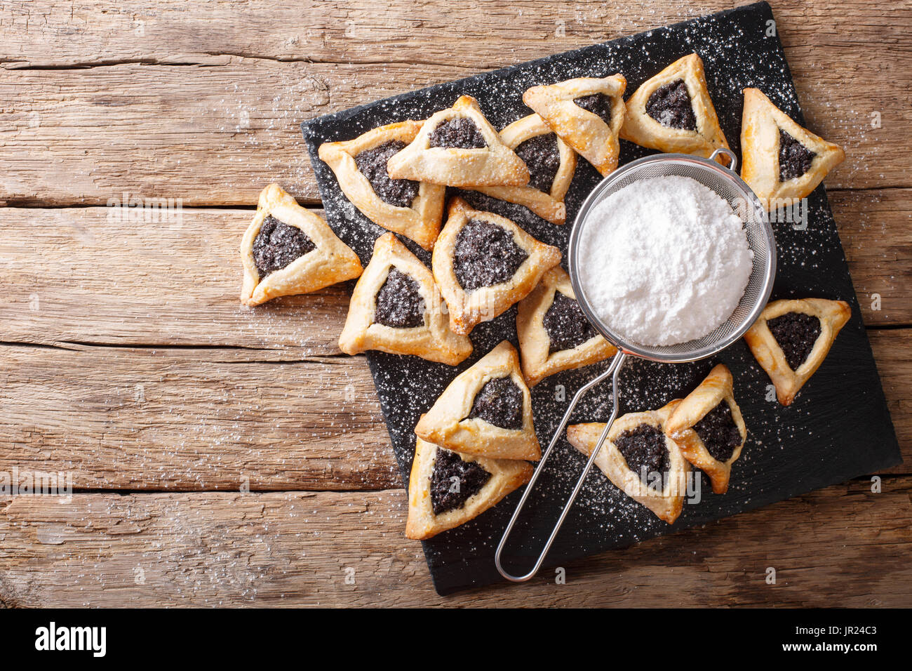 Hamentashen biscotti di forma triangolare con i semi di papavero per la festa di Purim holiday close-up sul tavolo. vista orizzontale dal di sopra Foto Stock