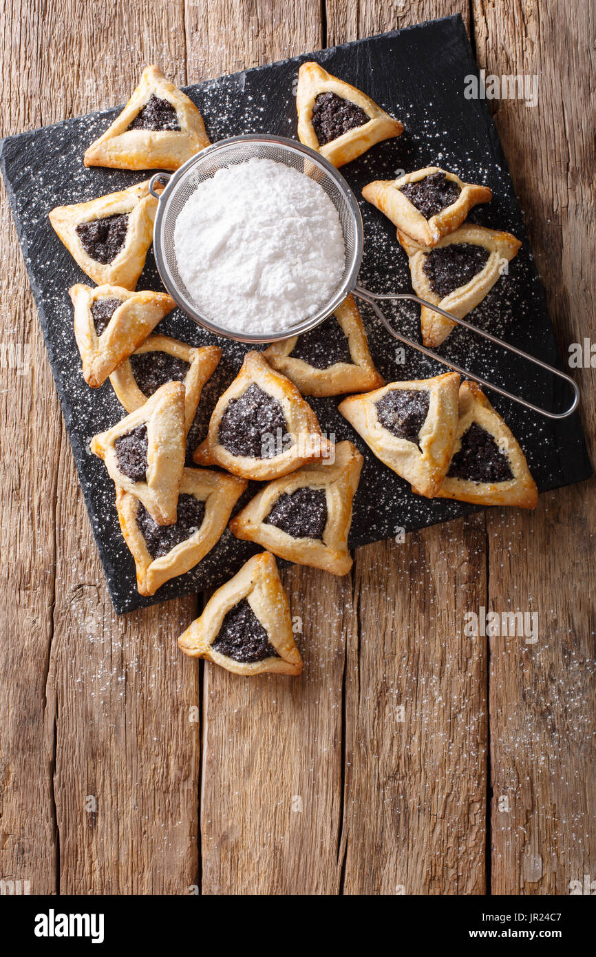 Hamentashen biscotti di forma triangolare con i semi di papavero per la festa di Purim holiday close-up sul tavolo. Vista verticale da sopra Foto Stock