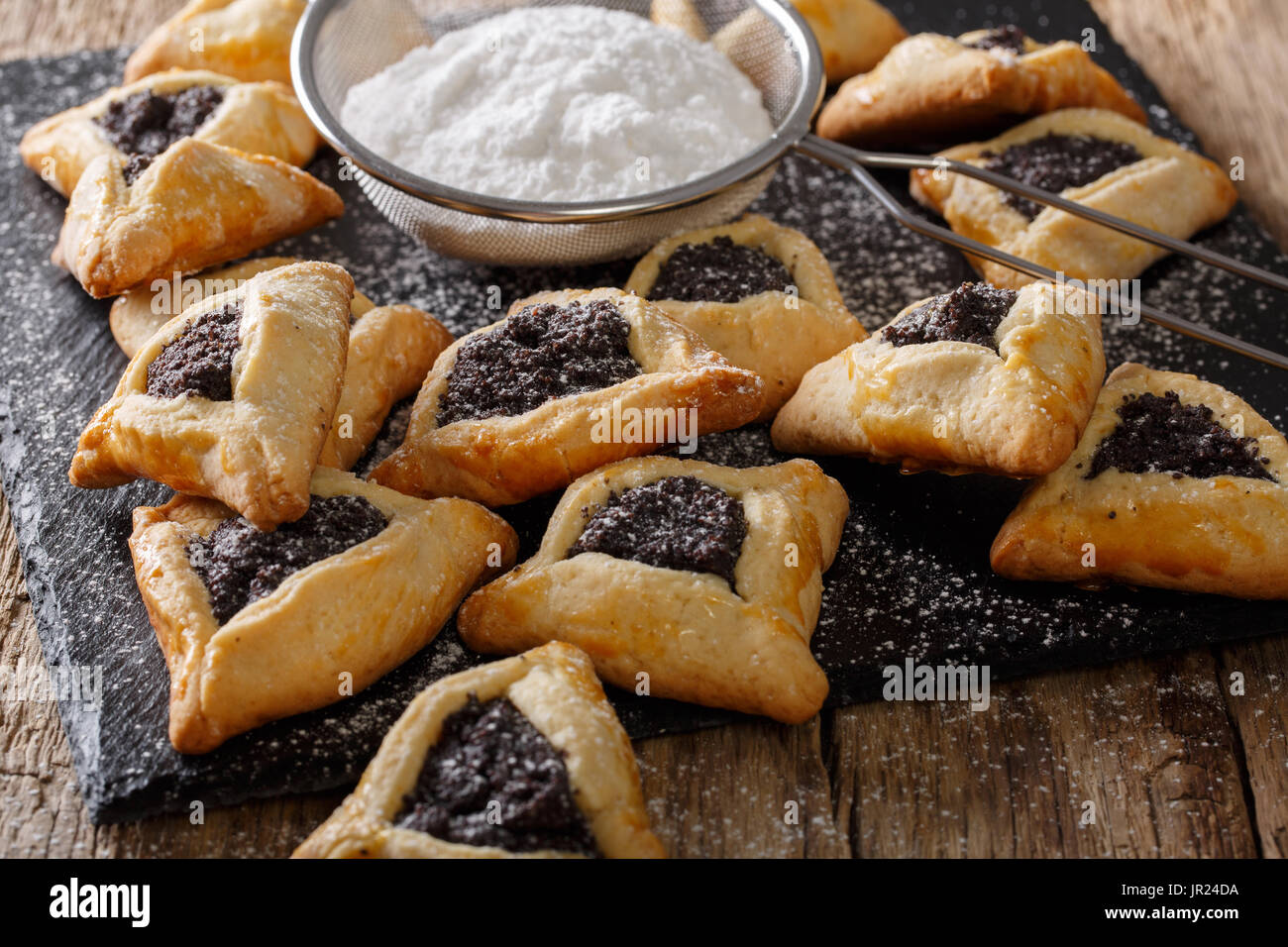 Hamantaschen ebraica biscotti con semi di papavero e zucchero in polvere vicino sul tavolo orizzontale. Foto Stock