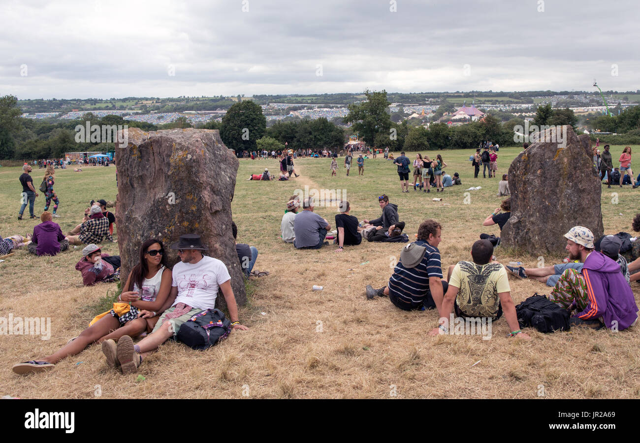 La gente seduta dal cerchio di pietra festival di Glastonbury Regno Unito Foto Stock