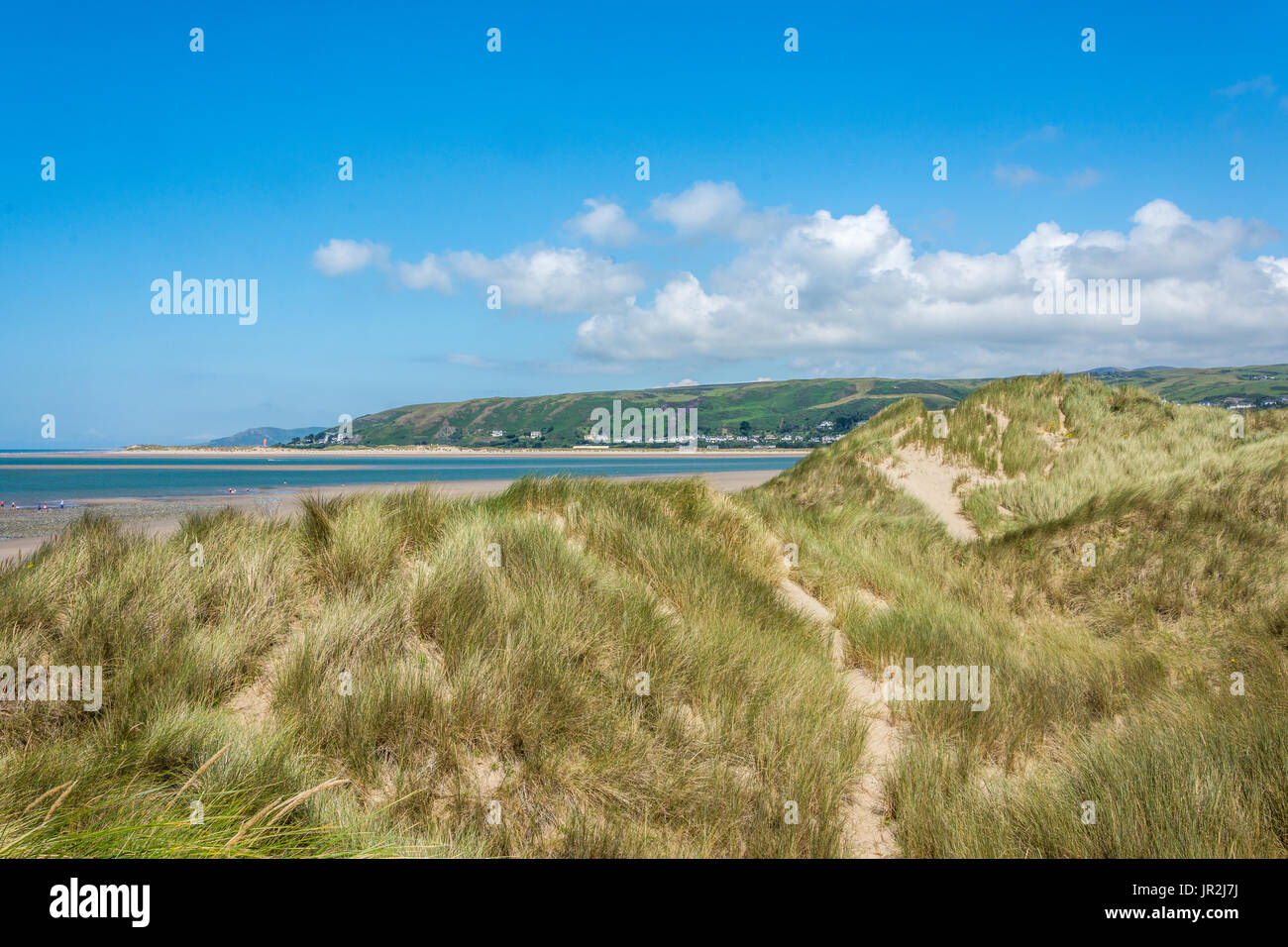 Lo straordinario paesaggio immagine del mare e la spiaggia dietro le dune di sabbia, con un bellissimo luminoso cielo blu e bianchi e soffici nuvole. Foto Stock