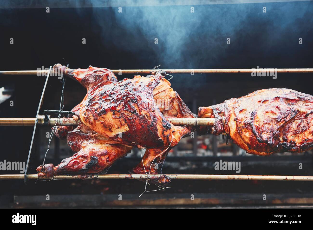 Preparare la carne per una festa o una celebrazione. Arrosto di tacchino e carne di maiale della gamba sul grill. Foto Stock
