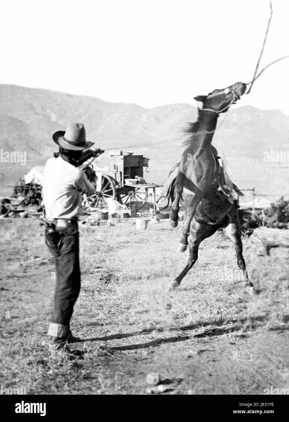 Cowboy tenendo una corda attorno al collo di un cavallo impennato sulle zampe posteriori; in background è un Chuck wagon. Cowboy del West Americano ha sviluppato una cultura personale dei propri, una miscela di frontiera e i valori di stile vittoriano che anche mantenuto la vestigia di cavalleria. Tali lavori pericolosi in condizioni di isolato di razza anche una tradizione di auto-dipendenza e individualismo, con grande valore dato all'onestà personale, esemplificato in canzoni e poesie. La media dei cowboy guadagnato circa un dollaro al giorno, più di cibo e, quando vicino alla casa ranch, un letto in il bunkhouse, solitamente una caserma-come edificio wit Foto Stock