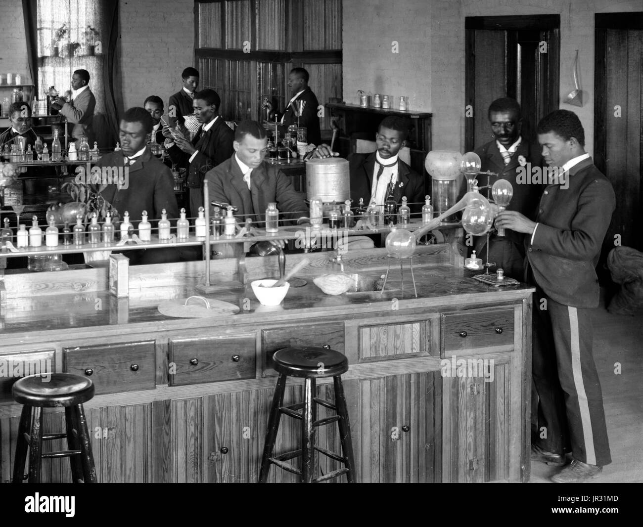 Laboratorio di Chimica/classe con studenti presso l istituto di Tuskegee, Tuskegee, Alabama. George Washington Carver si erge secondo da destra, rivolto verso la parte anteriore (incorniciato dalla porta). George Washington Carver (1864 - Gennaio 5, 1943) era un afro-americano di scienziato, botanico, educatore e inventore nato in schiavitù. Nel 1891 ha frequentato e studiato botanica alla Iowa State Agricultural College dove egli fu il primo studente nero e in seguito ha insegnato come il primo nero membro della facoltà. La sua reputazione si basa sulla sua ricerca e promozione di colture alternative per il cotone, come arachidi, semi di soia e sw Foto Stock
