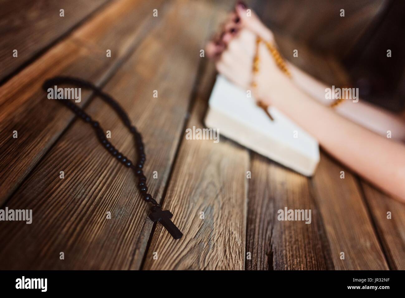 Giovani pregando womans mani con il rosario in legno e la Sacra Bibbia. Concetto di religione Foto Stock