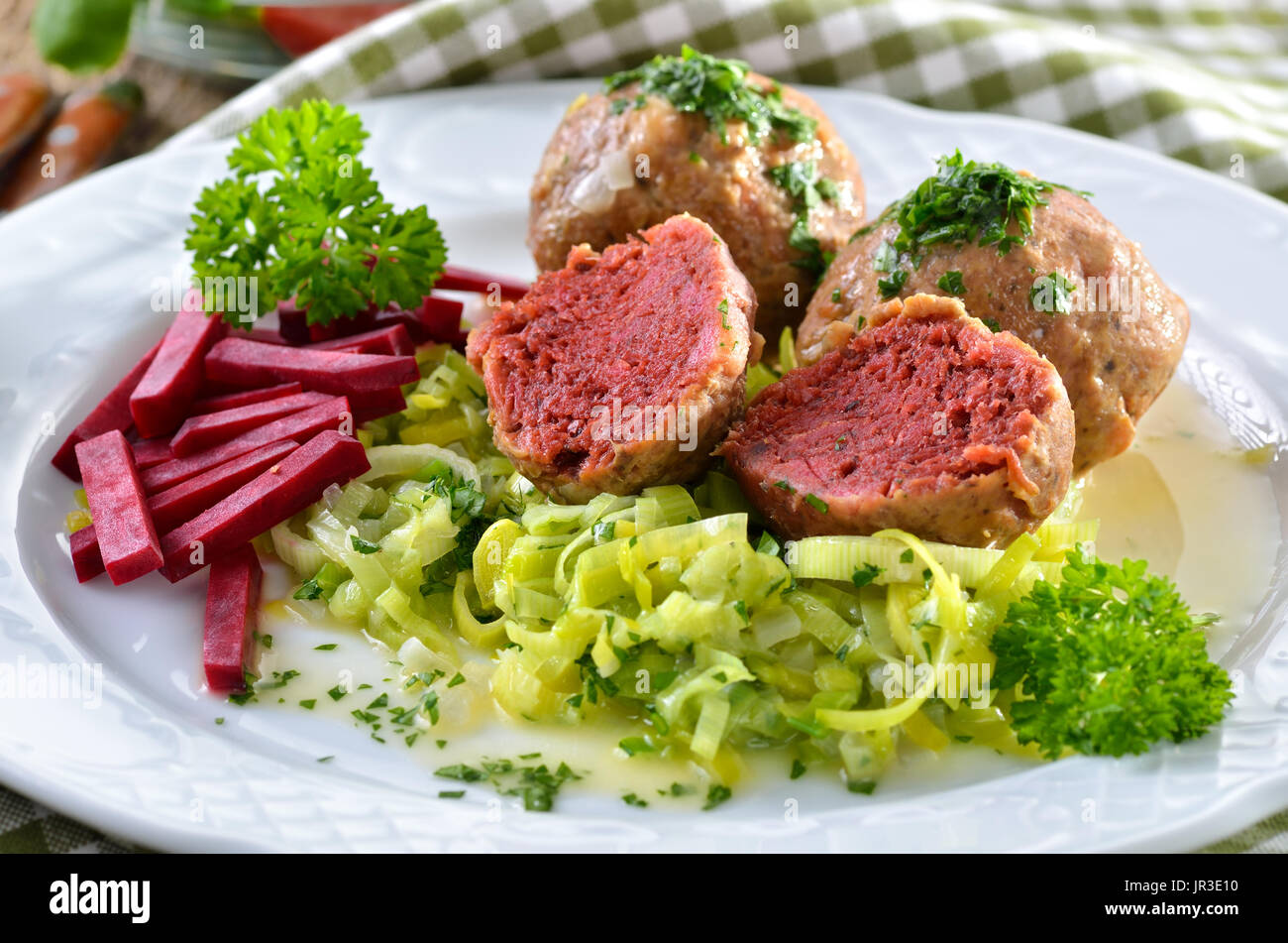 La barbabietola rossa dell'Alto Adige gnocchi di pane su porri, servita su un vecchio tavolo in legno Foto Stock