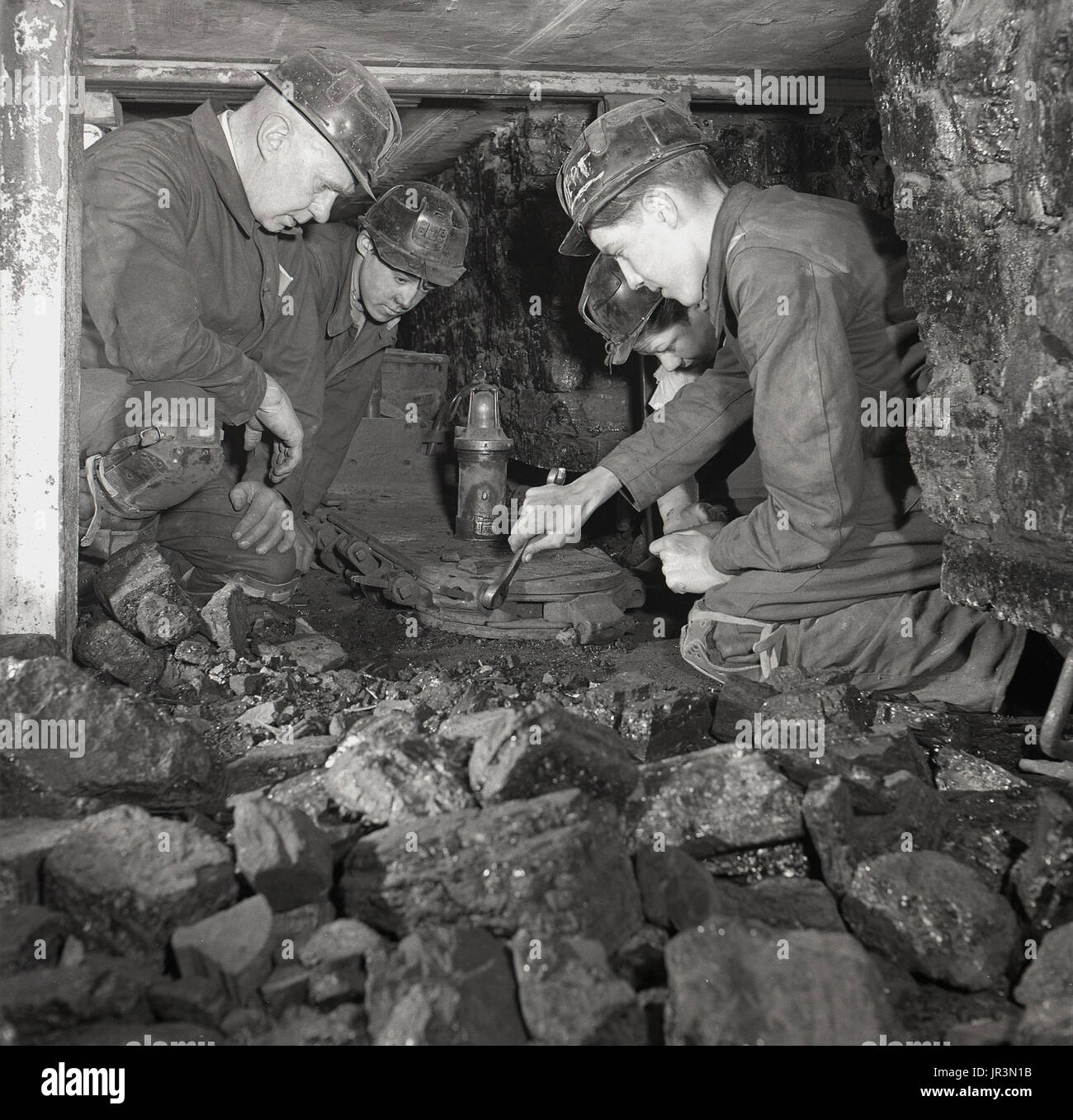 1948, storico Inghilterra, giovane apprendista di data mining o partecipante utilizza una chiave per serrare i bulloni su un metallo engineeing attrezzo sotto l'occhio vigile del suo supervisore o tuitor. Foto Stock