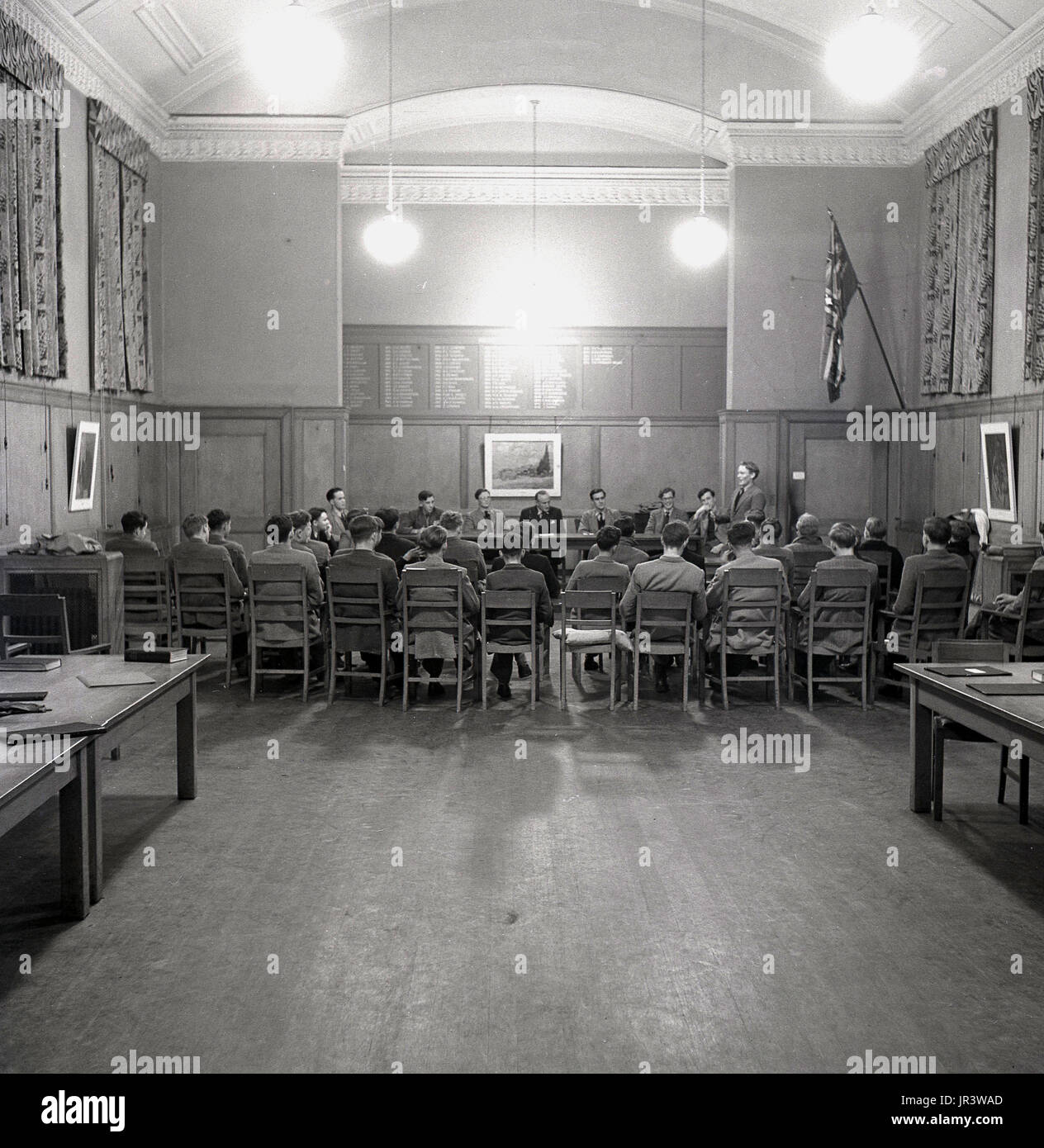 1948, storico, una pupilla addresssing gli altri alunni e maestri della scuola nella sala principale a Haileybury public school, un tradizionale british boys solo Boarding School, Hertford, Inghilterra, Regno Unito. Foto Stock