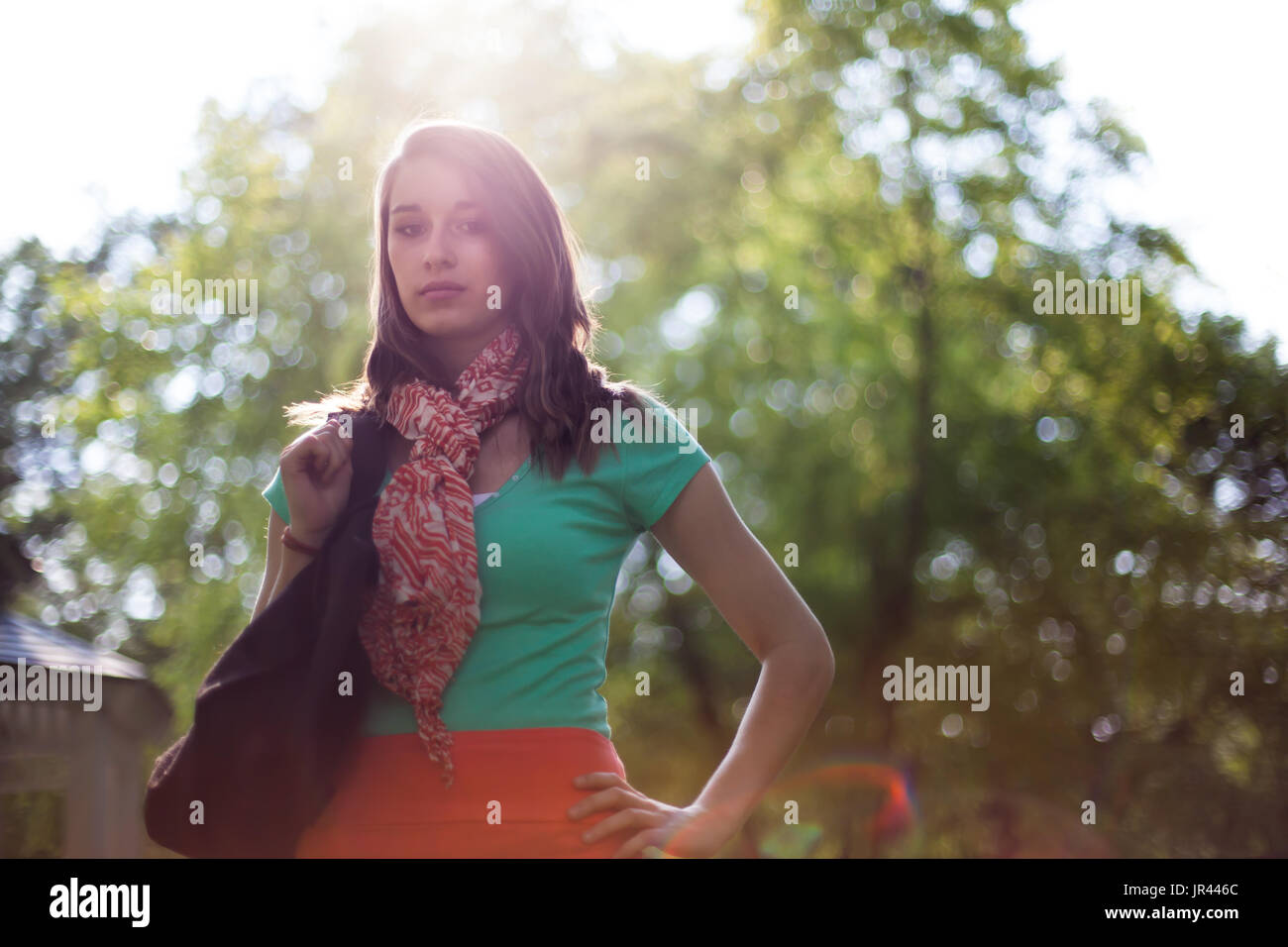 Bella giovane donna con eco-friendly tessuto borse per lo shopping. La luce solare naturale e flare ottico con alberi in background. Foto Stock