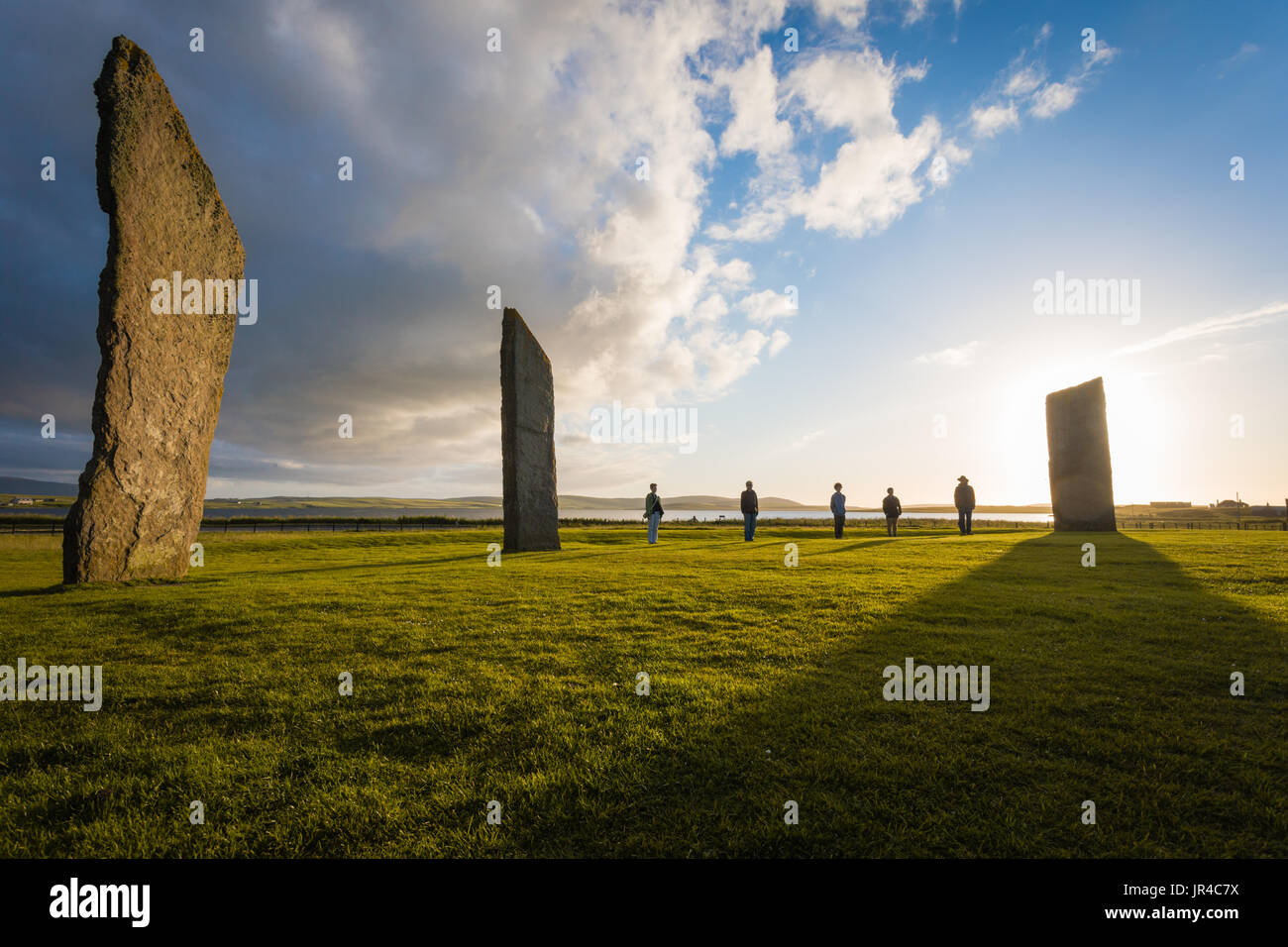 Un gruppo di turisti si presentano come le pietre a Standing Pietre di Stenness, Orkney sito neolitico Foto Stock