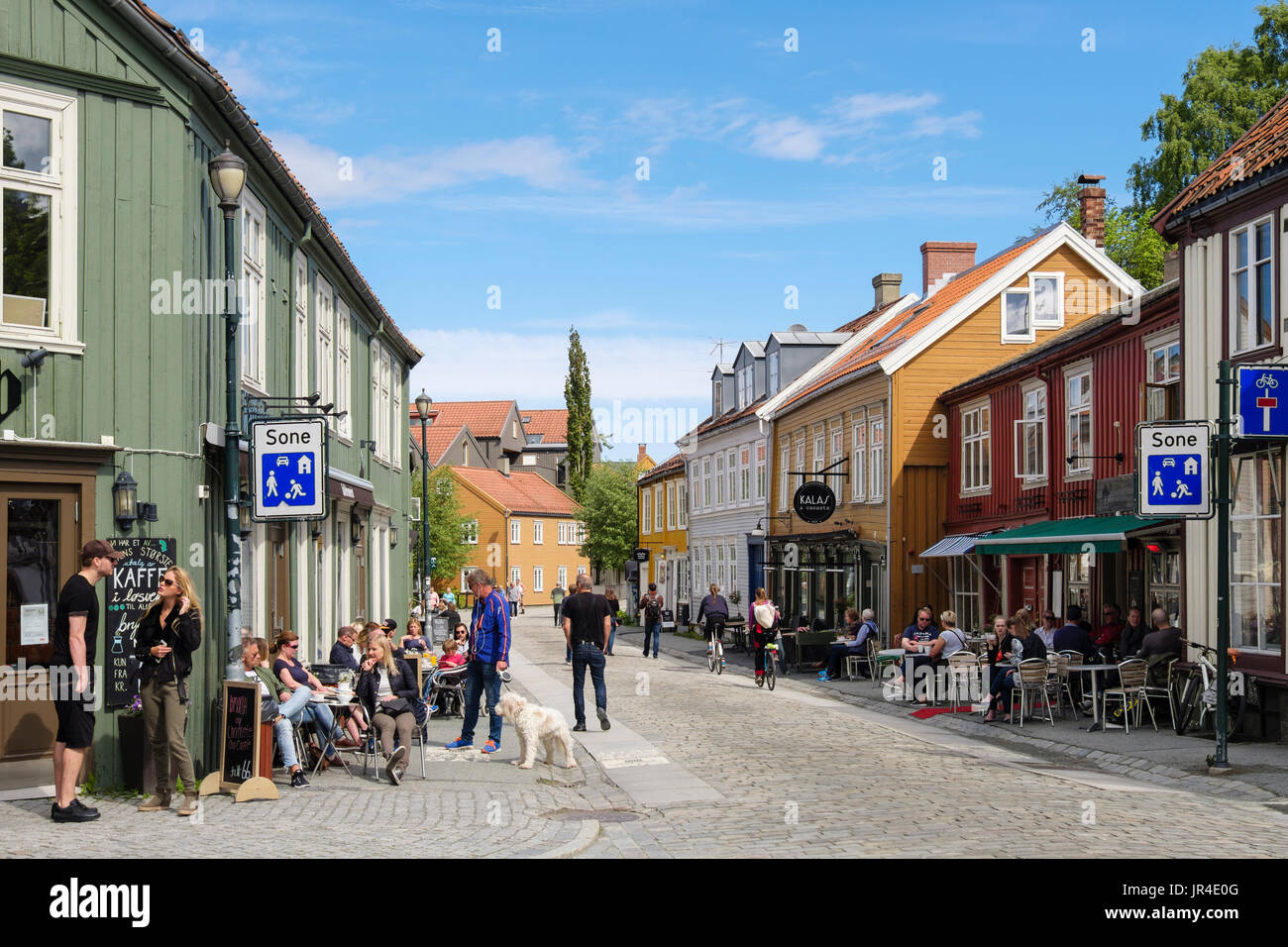 Caffè e persone nella zona pedonale strada di ciottoli con scena di vecchi edifici. Nedre Bakkelandet, Bakke Landet, Trondheim, Norvegia Foto Stock