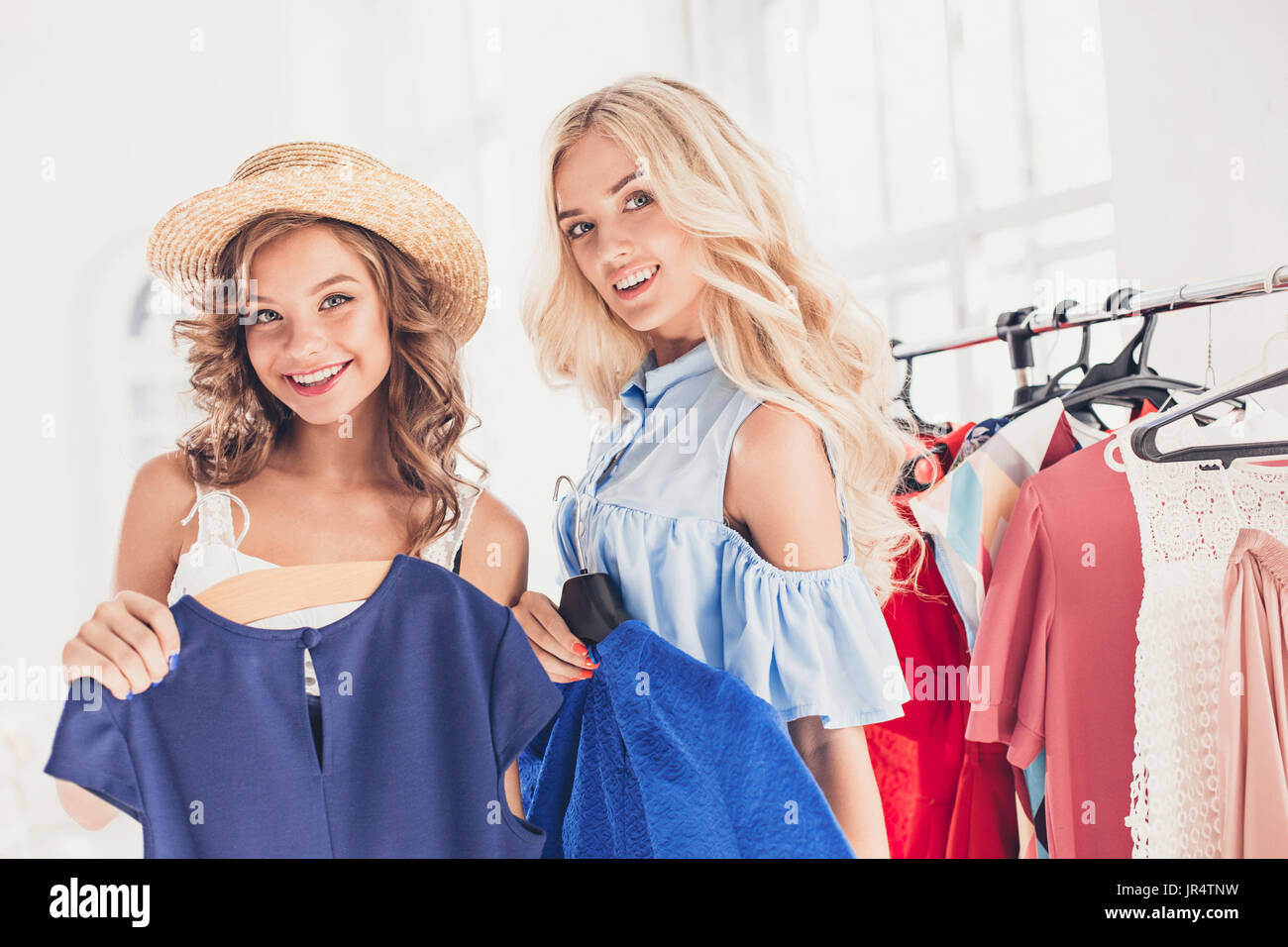 I due giovani ragazze guardando gli abiti e provare su di esso mentre scegliendo al shop Foto Stock