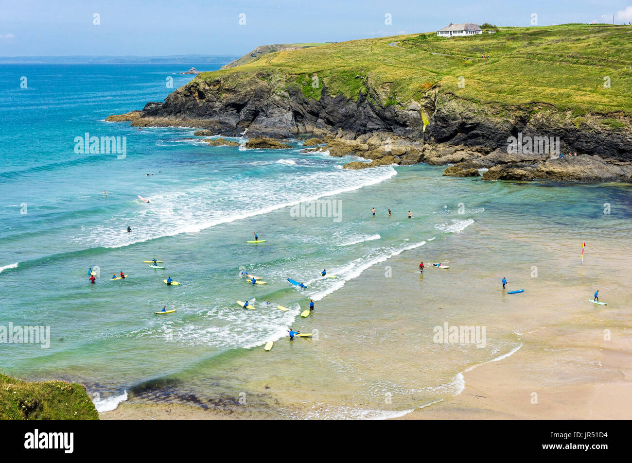 Surf sulla spiaggia di Poldhu Cove con persone che imparano a fare surf in Cornovaglia, Regno Unito Foto Stock