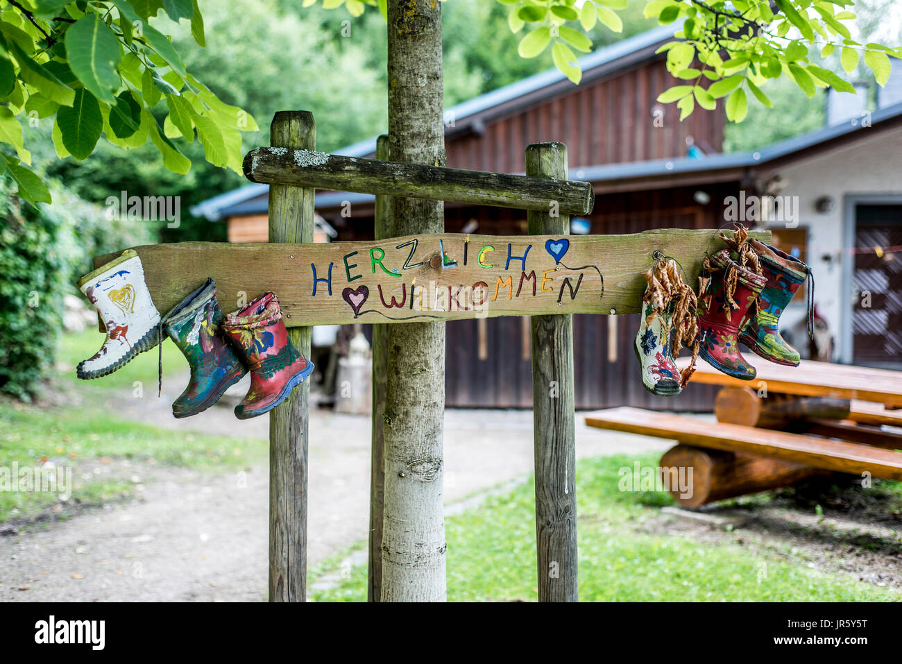 Etichetta di partito stivali di gomma segno della foresta di legno tree house Herzlich Willkommen significa Benvenuti Foto Stock