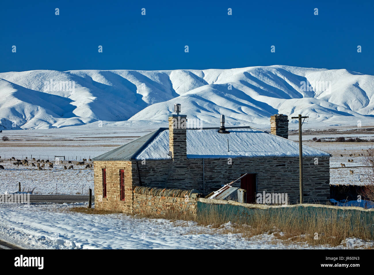 Storico cottage in pietra e gamma di Ida in inverno, Colline Creek, Maniototo di Central Otago, Isola del Sud, Nuova Zelanda Foto Stock