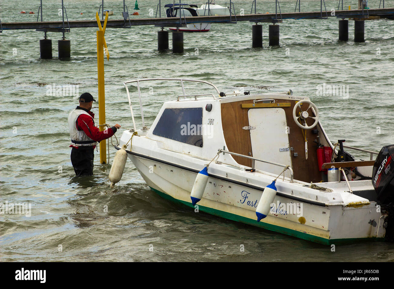 Un proprietario di imbarcazione portando la sua piccola fibra di vetro barca verso la riva in Warsash, Hampshire ad un rimorchio di attesa per portarlo fuori dall'acqua Foto Stock