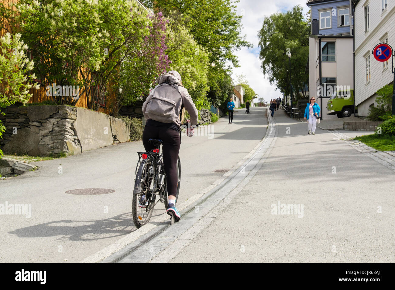 Persona in sella a una bicicletta utilizzando la bicicletta sollevare a correre in salita su una strada in salita nella città vecchia. Brubakken, Trondheim, Sør-Trøndelag, Norvegia e Scandinavia Foto Stock