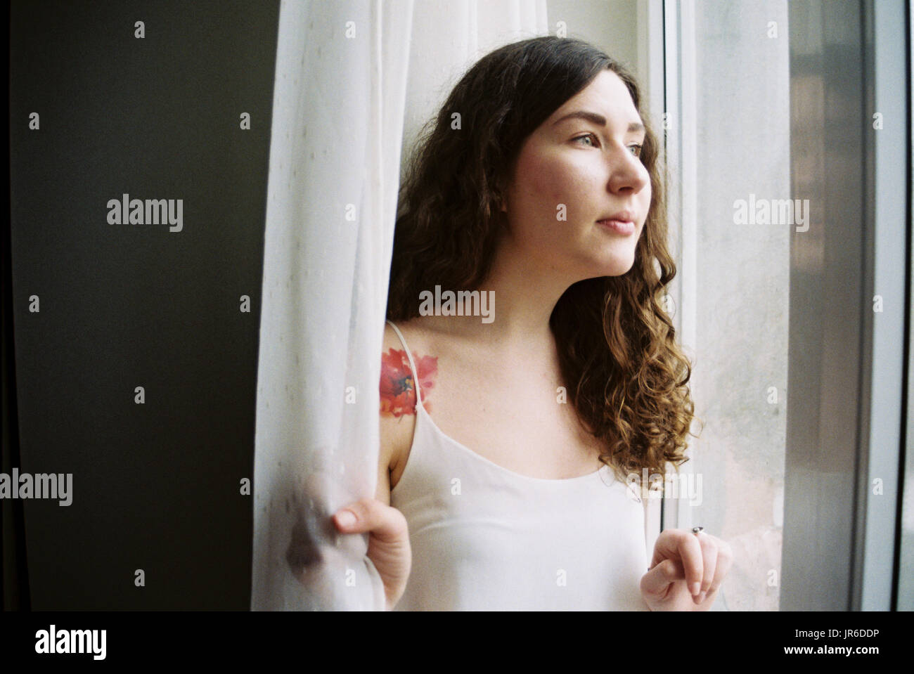 Donna che guarda fuori da una finestra Foto Stock