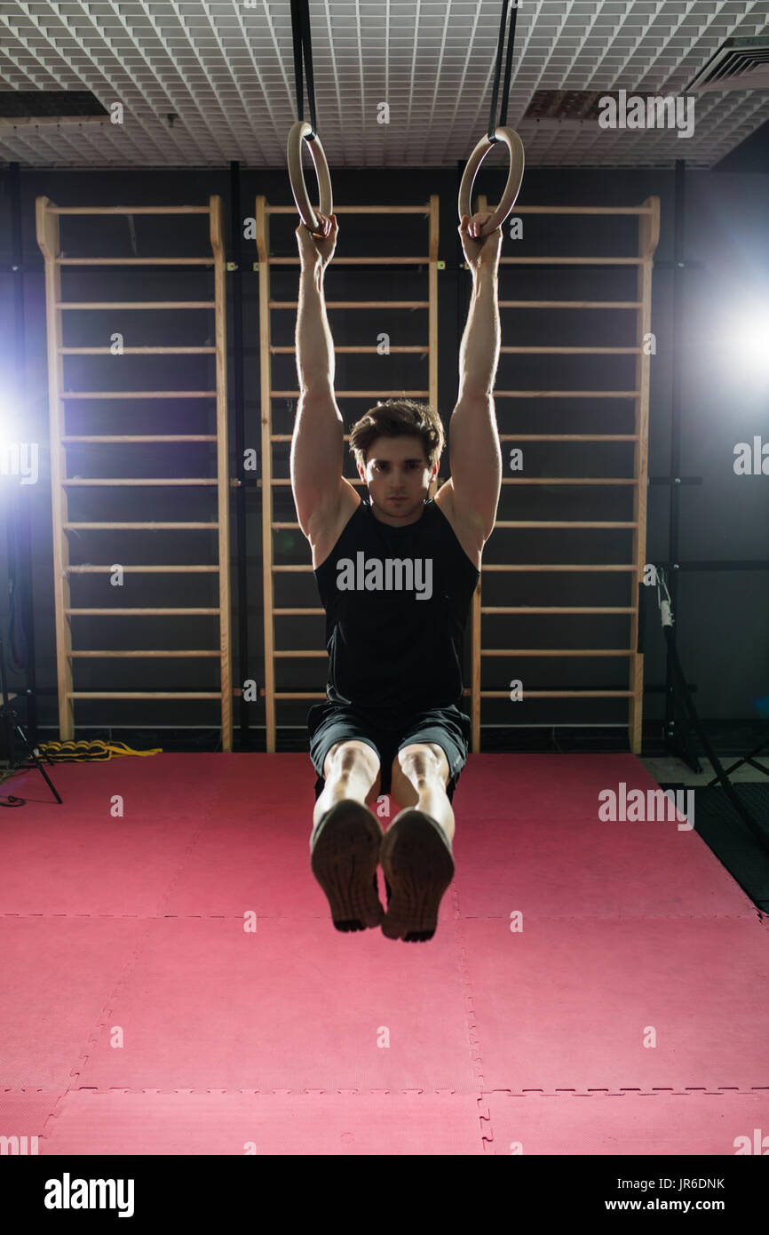 Fitness uomo bello fare immersione esercizio utilizzando anelli in palestra Foto Stock