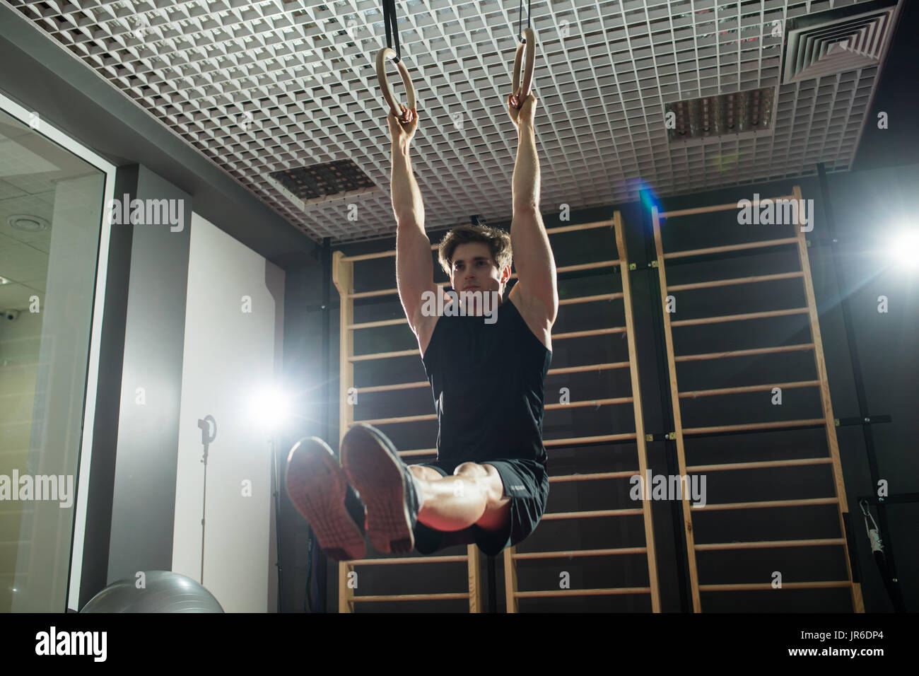 Fitness uomo bello fare immersione esercizio utilizzando anelli in palestra Foto Stock