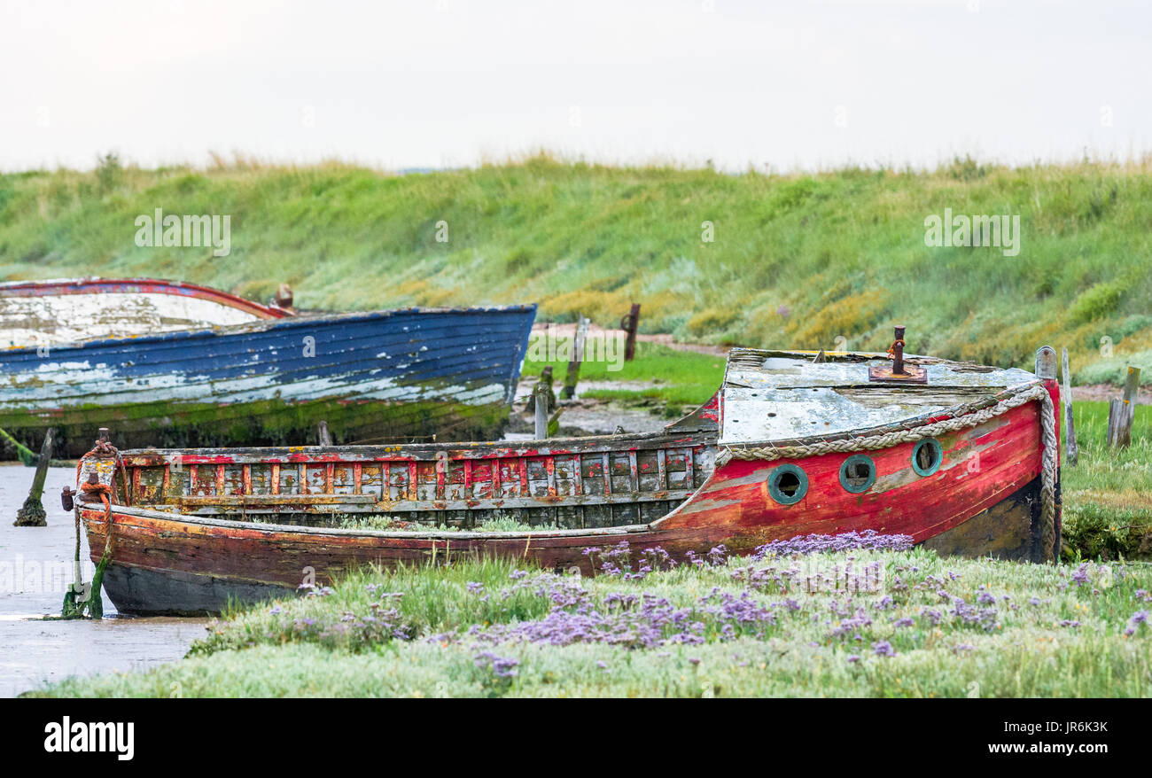 Spiaggiata marciume barche di legno nell'estuario fangoso a Orford, Suffolk. Foto Stock