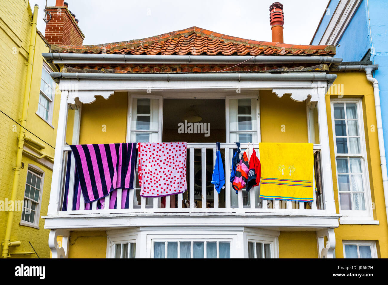 Asciugamani essiccazione su un bianco railed balcone di un dipinto di giallo casa. Foto Stock