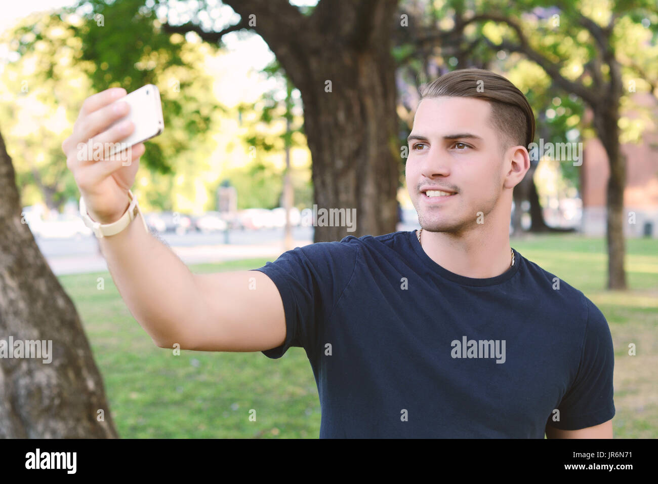 Giovane uomo latino tenendo un selfie con lo smartphone al parco. All'esterno. Foto Stock