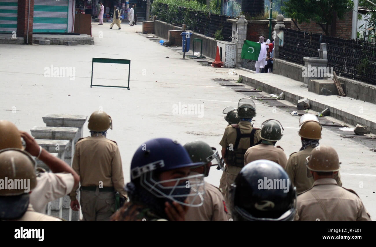 Srinagar Kashmir. 4° agosto 2017. Mascherato contestatori del Kashmir pakistano detiene il flag come la polizia indiana la visione di anello d una protesta nell'area del Centro Cittadino di .Le autorità dello stato aveva bloccato le porte della grande moschea per gli ultimi sei settimane non consentendo alle persone di offrire preghiere alla moschea.e civili di uccisioni in Kashmir. Credito: Sofi Suhail/Alamy Live News Foto Stock