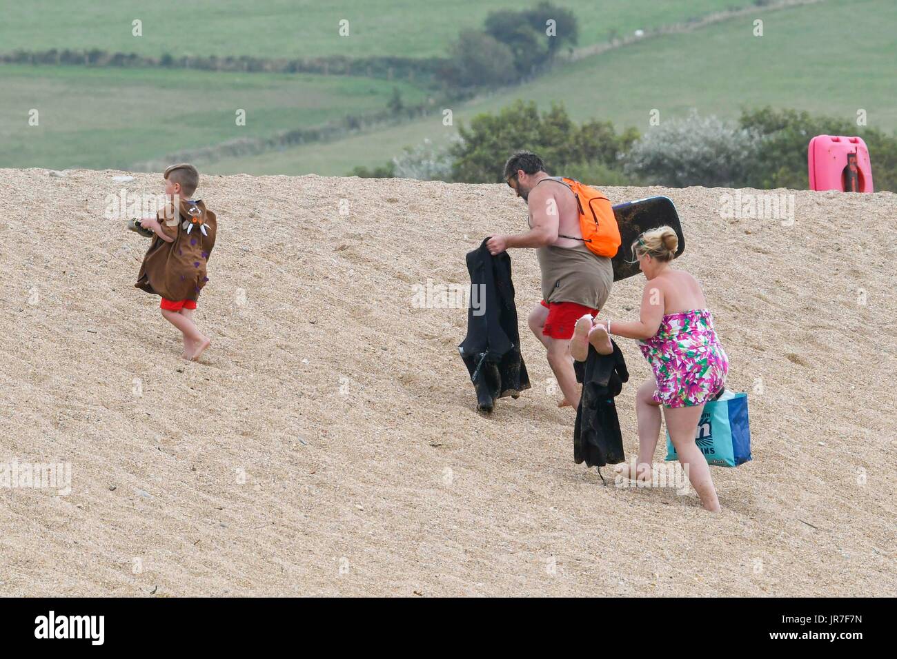 West Bay, Dorset, Regno Unito. 4 agosto 2017. Regno Unito Meteo: una famiglia di lasciare la spiaggia come cloud e una brezza chiily ed entra in off il mare alla stazione balneare di West Bay nel Dorset. Photo credit: Graham Hunt/Alamy Live News Foto Stock