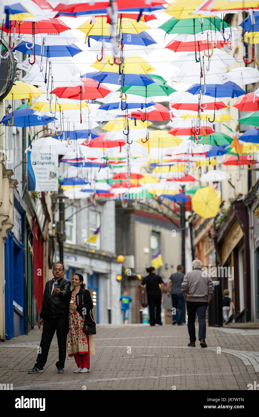 Giovane tenendo selfie su un slaney street in enniscorthy Irlanda decorate con ombrelloni flottante per il rockin' food festival Foto Stock
