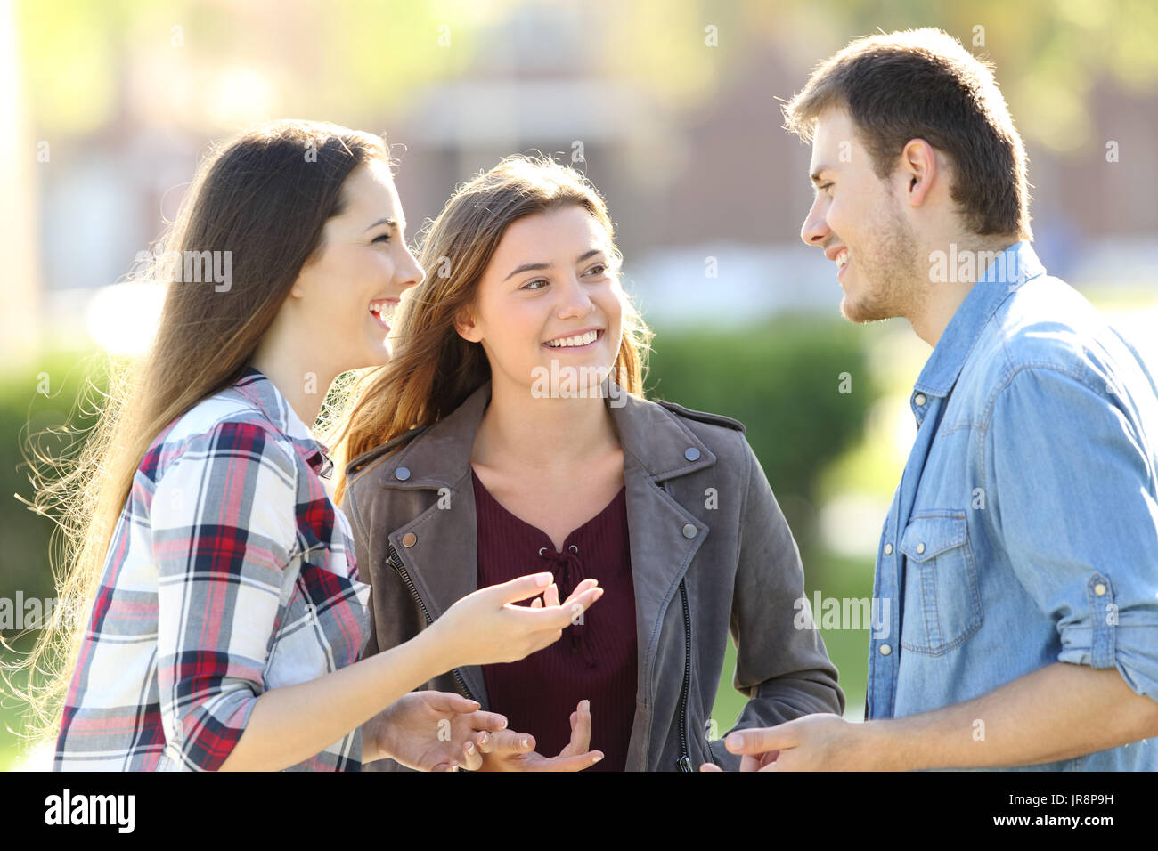 Tre amici felice avente una conversazione e ridere in strada Foto Stock