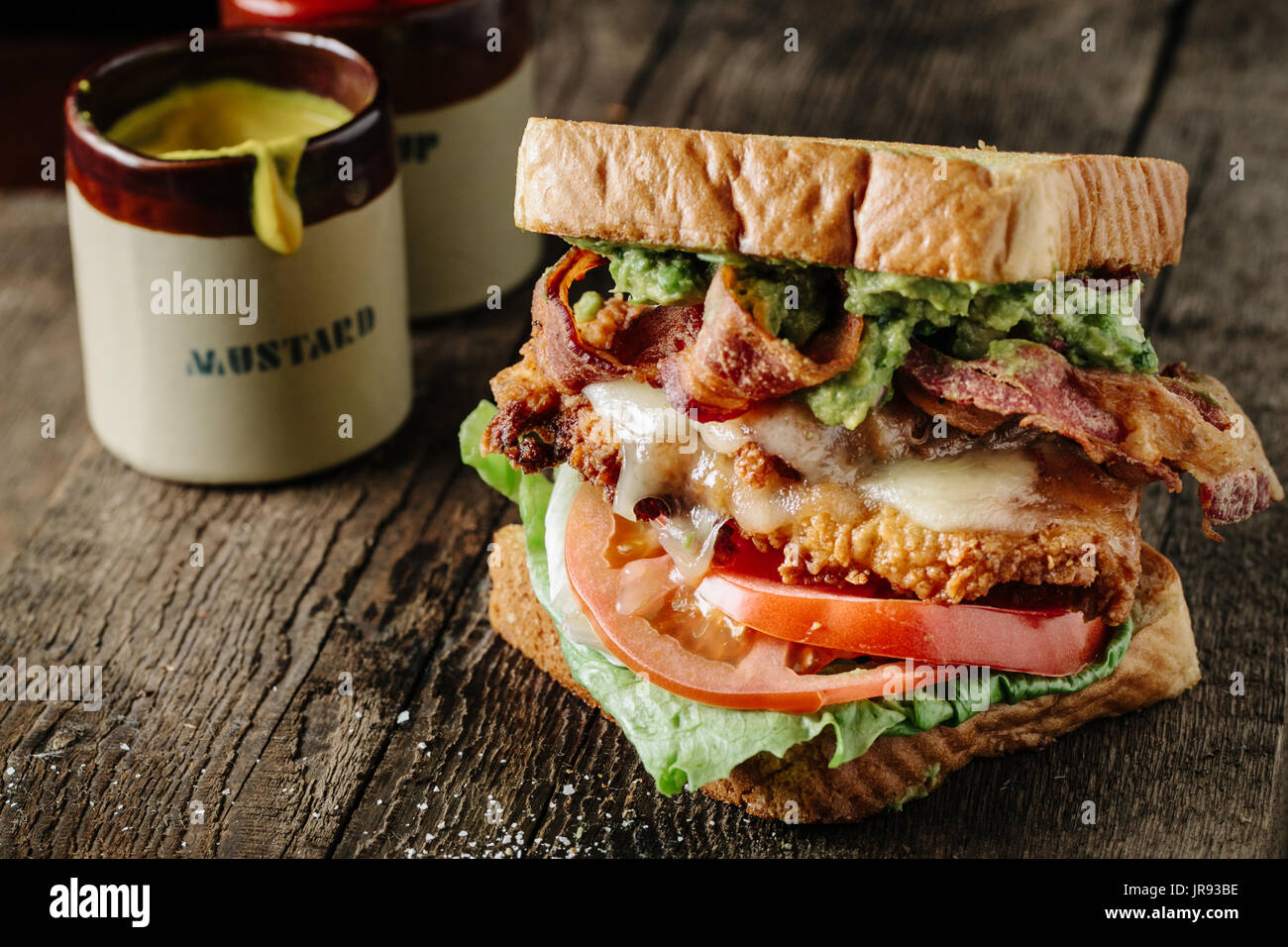 Pollo e avocado BLT sandwich con mostarda e ketchup per bottiglie Foto Stock