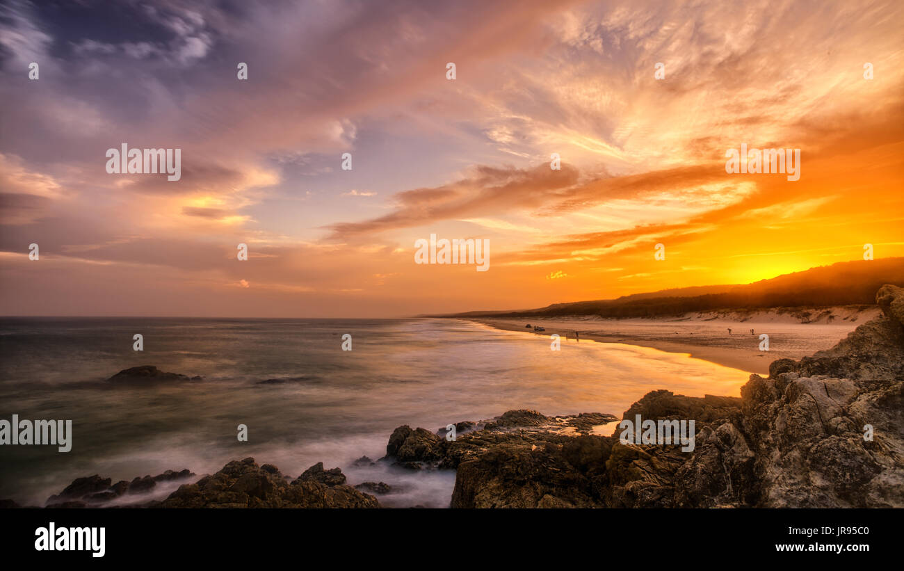 Impostazione del sole sopra la spiaggia, fotografata da una costa rocciosa via a Stradbroke Island, in Australia. Foto Stock