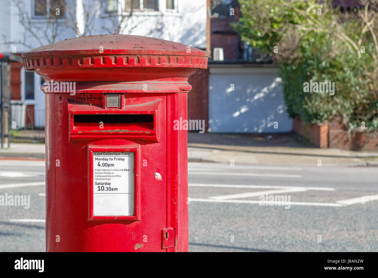 Red English post box set contro un de-focalizzato sullo sfondo di strada Foto Stock